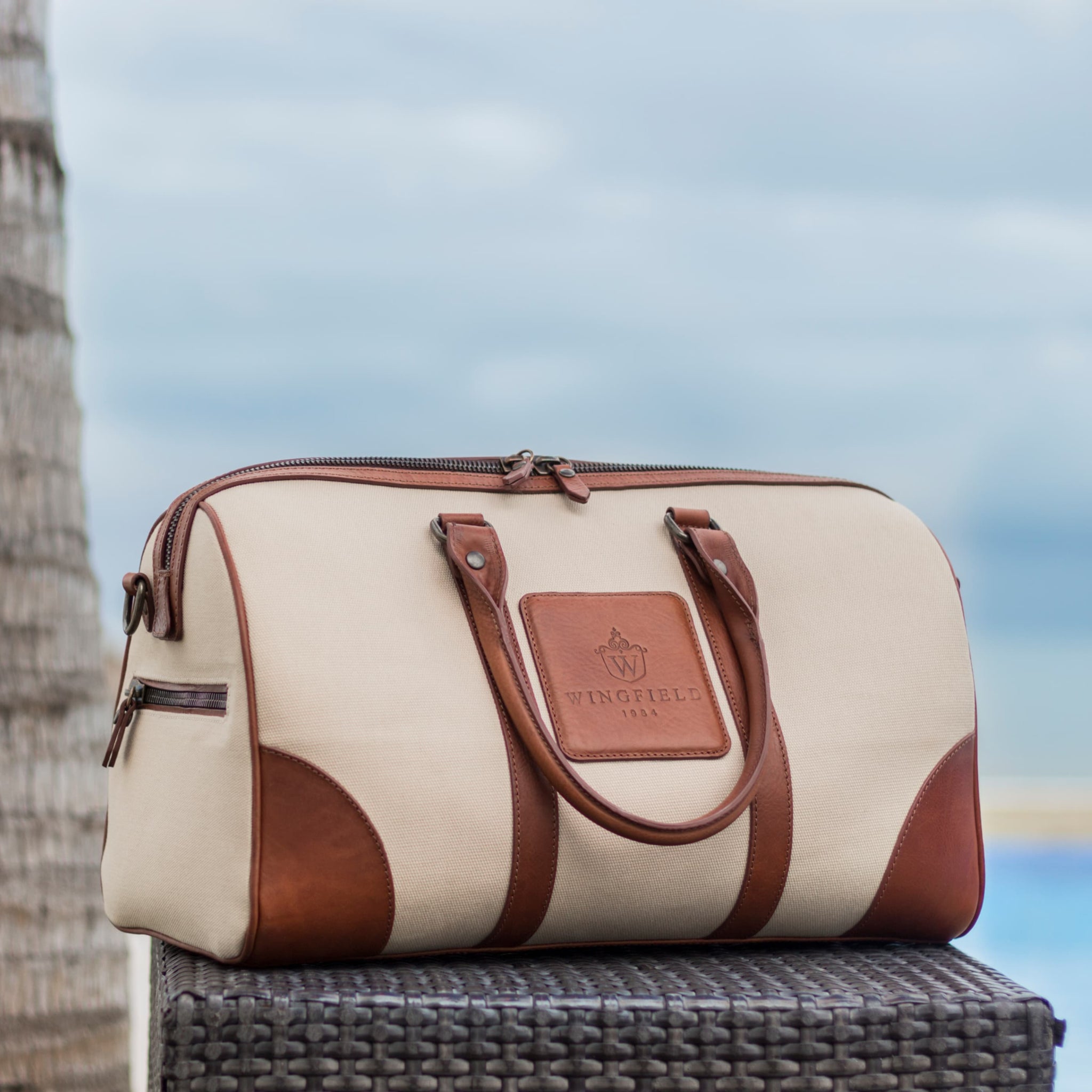 Compact canvas and leather duffel bag with top handles, adjustable shoulder strap, leather accents, zip closure travel ready