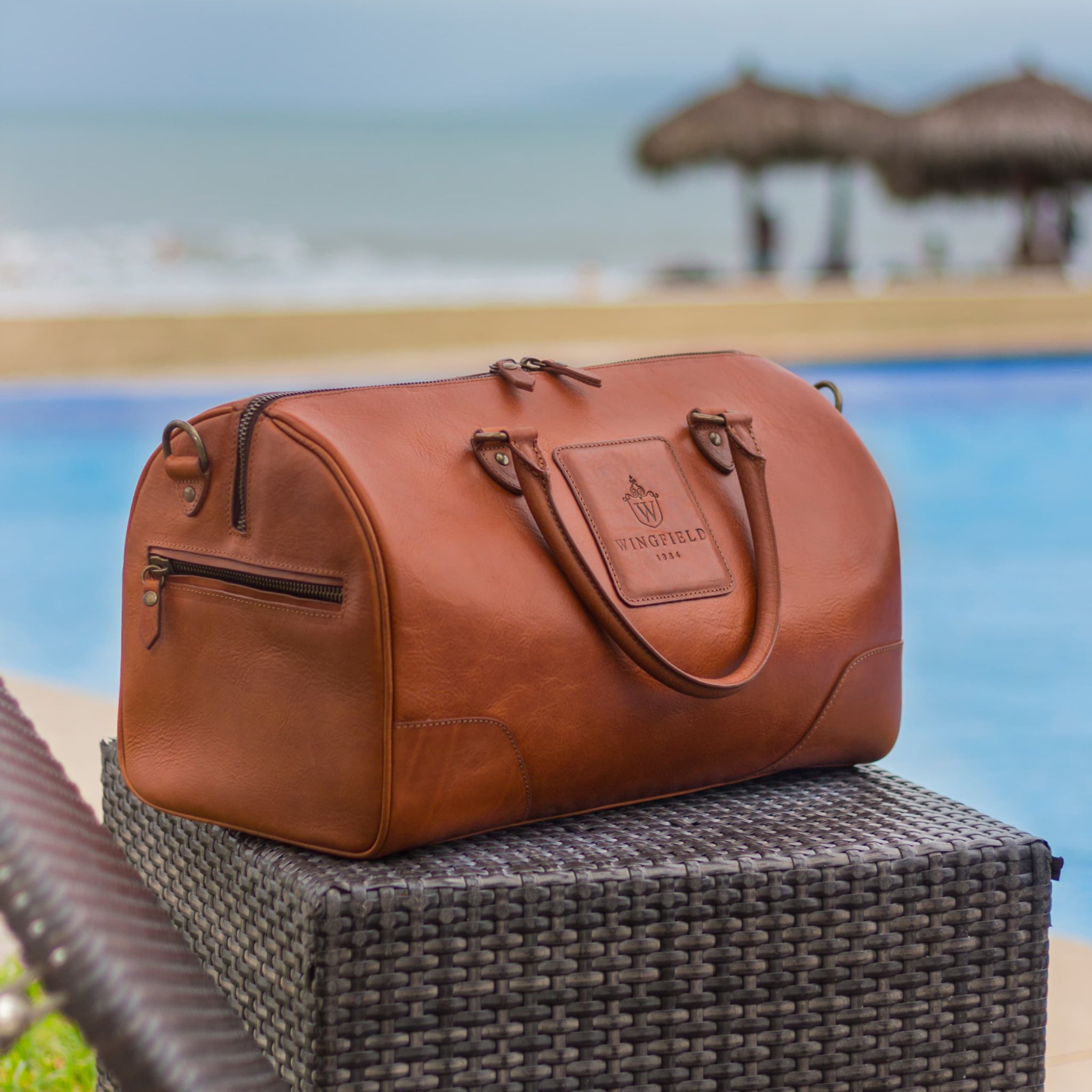 Full-grain leather duffel bag with zip closure, structured shape, carry handles, and adjustable shoulder strap, compact sleek