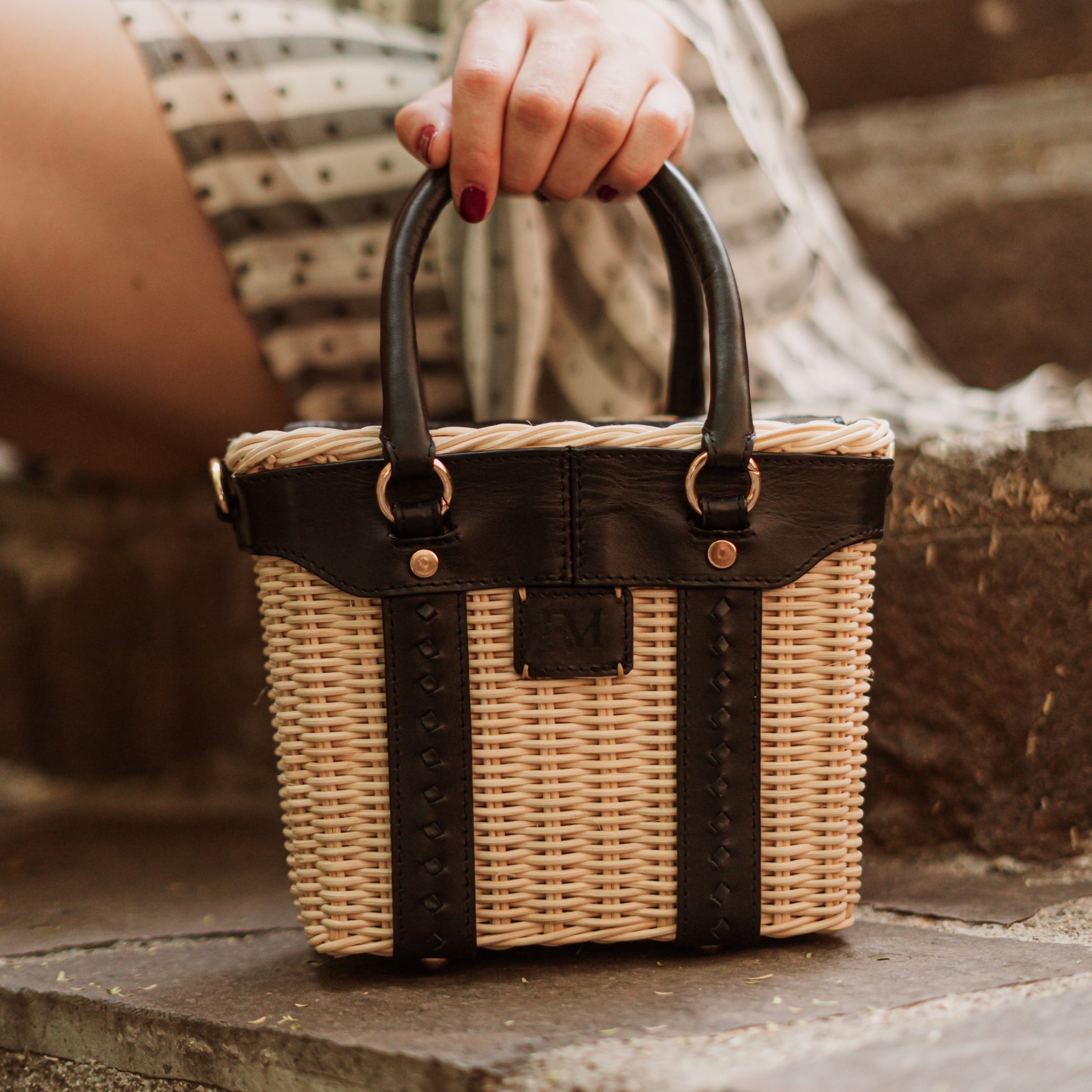 Leather and wicker tote bag with structured body, dual top handles, inner lining, and chain strap, elegant handcrafted feel