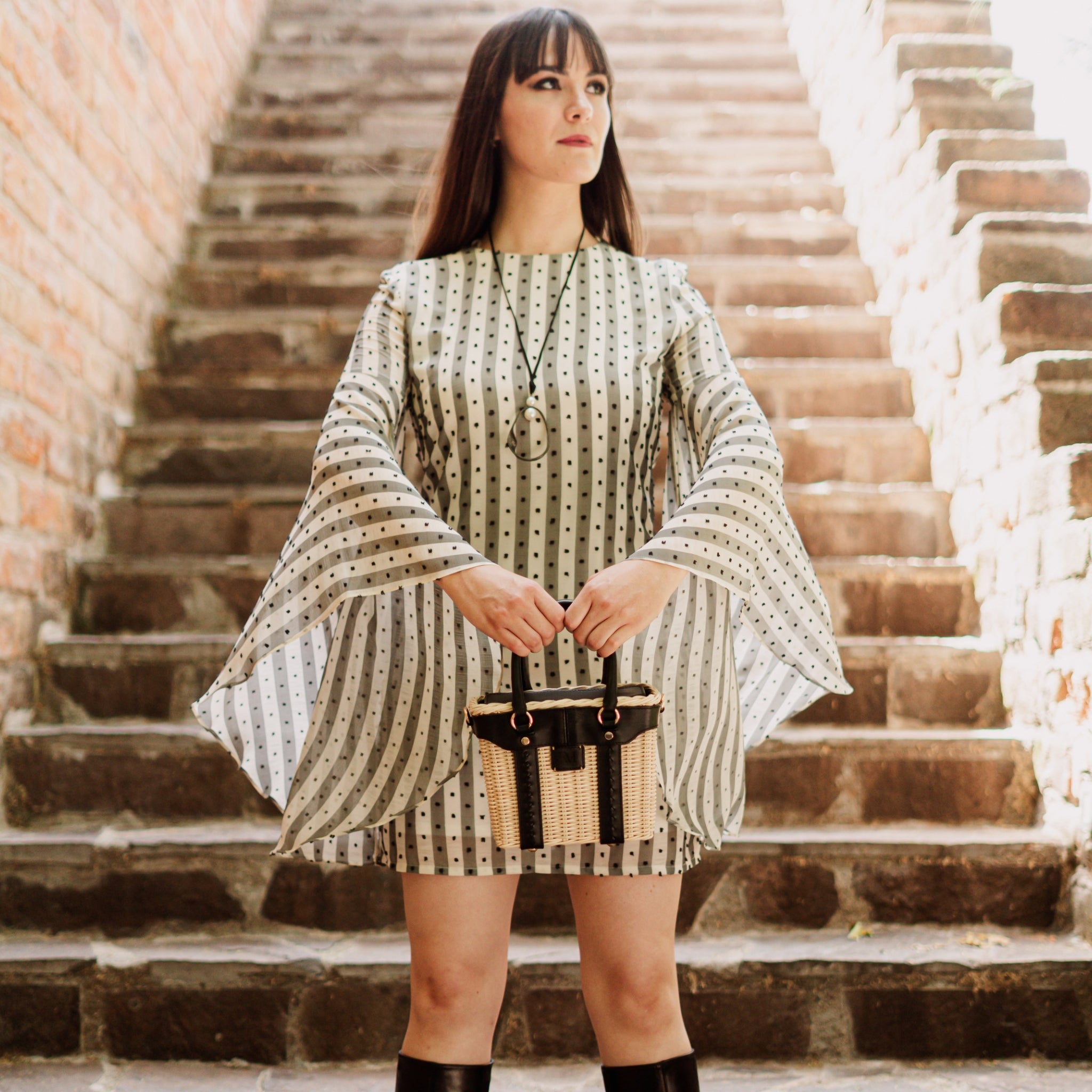 Leather and wicker tote bag with structured body, dual top handles, inner lining, and chain strap, elegant handcrafted feel