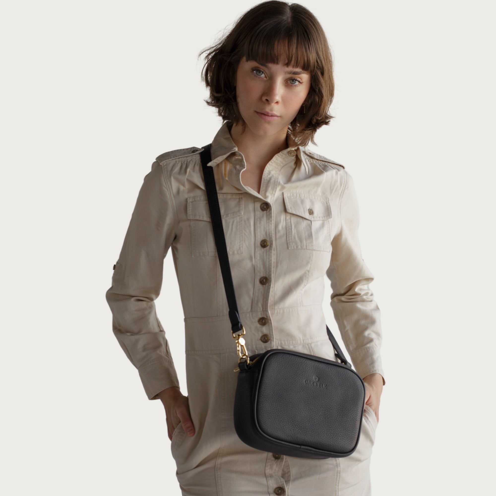 Black leather camera bag with gold zipper, adjustable crossbody strap, and compact design — ideal for essentials on the go.