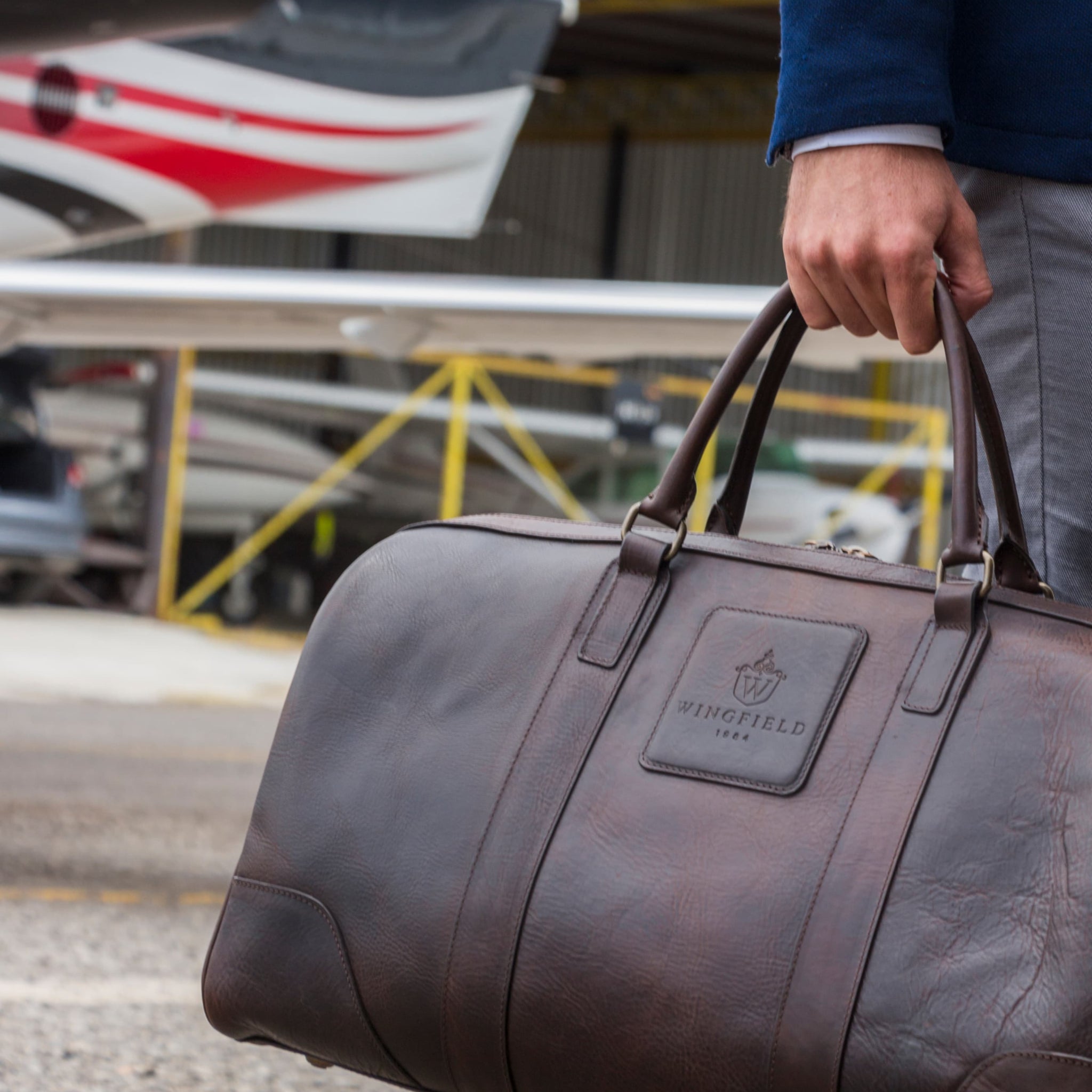 Large full-leather duffel bag with zip closure, structured body, carry handles, adjustable shoulder strap, ideal for travel.