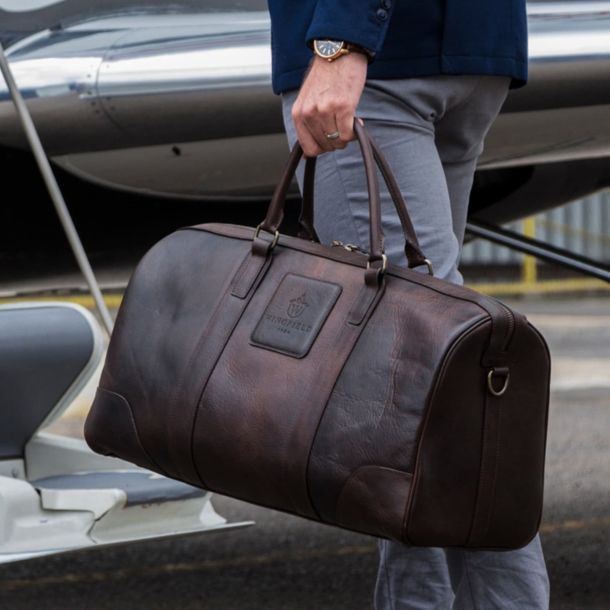 Large full-leather duffel bag with zip closure, structured body, carry handles, adjustable shoulder strap, ideal for travel.