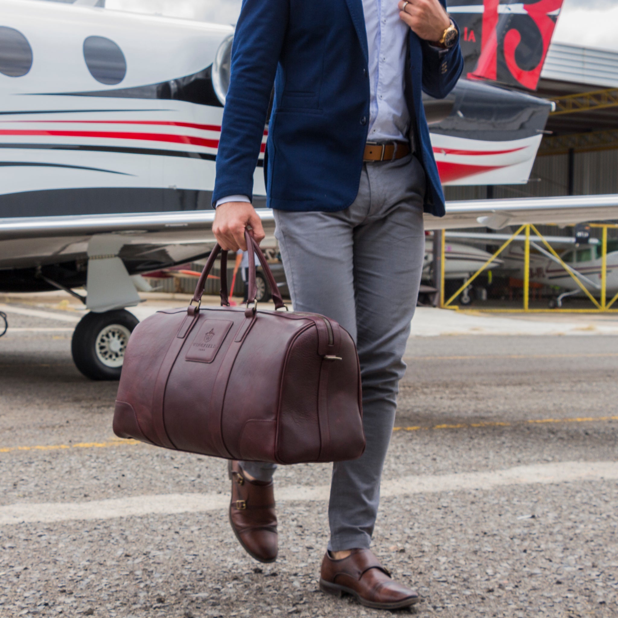 Large full-leather duffel bag with zip closure, structured body, carry handles, adjustable shoulder strap, ideal for travel.