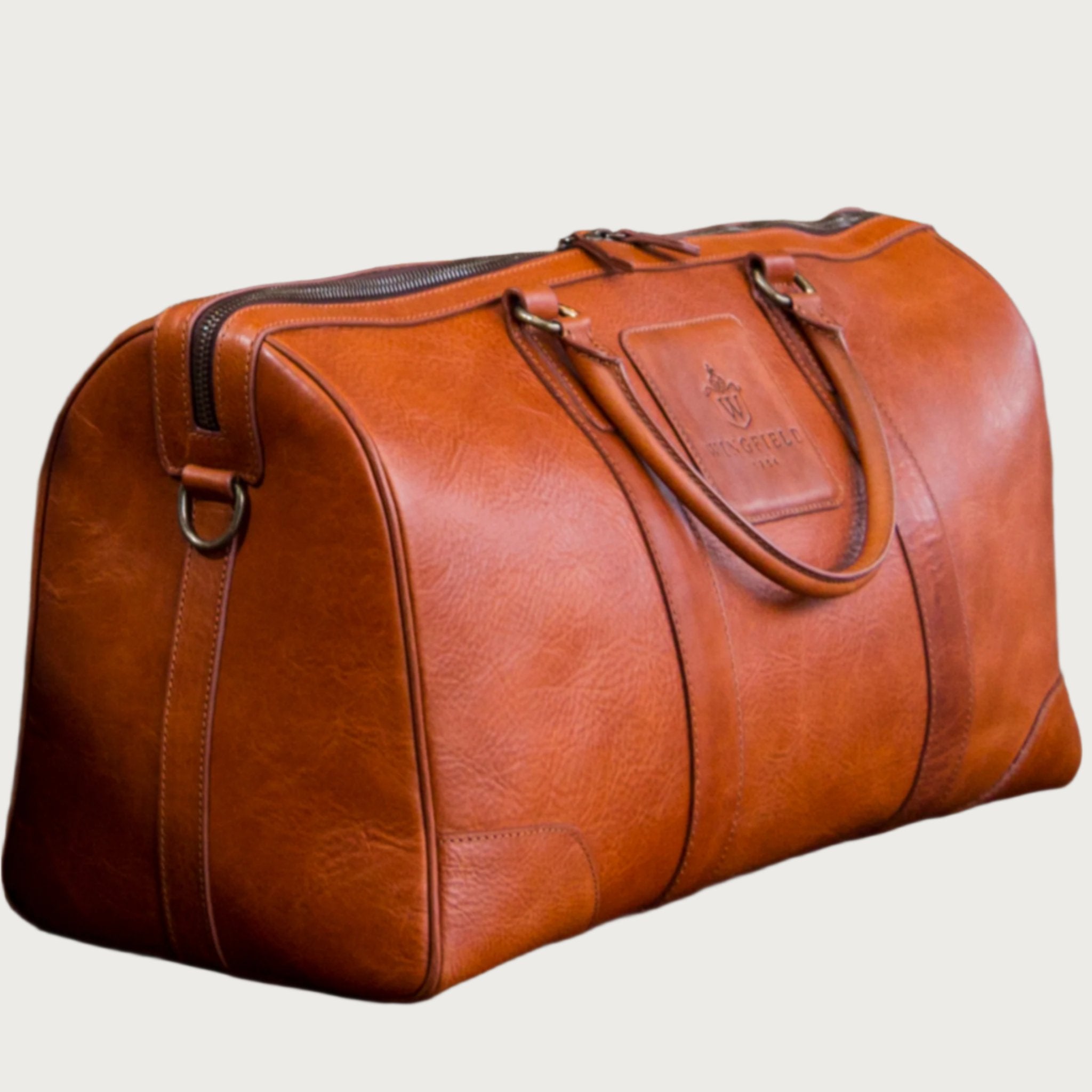 Large full-leather duffel bag with zip closure, structured body, carry handles, adjustable shoulder strap, ideal for travel.