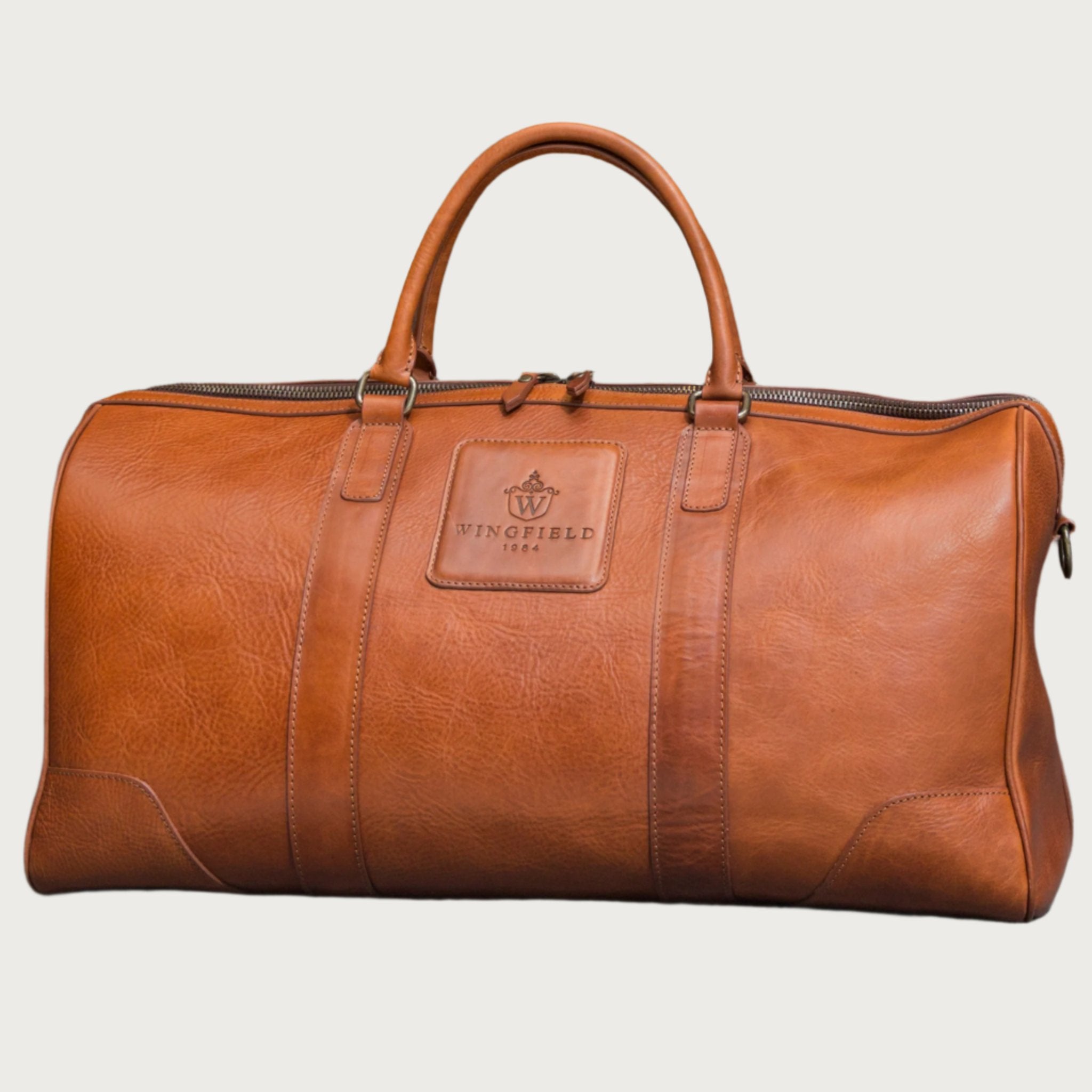 Large full-leather duffel bag with zip closure, structured body, carry handles, adjustable shoulder strap, ideal for travel.