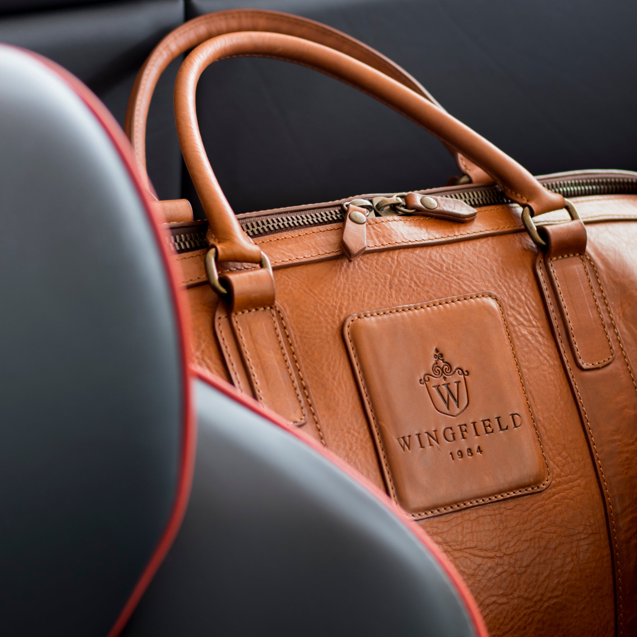 Large full-leather duffel bag with zip closure, structured body, carry handles, adjustable shoulder strap, ideal for travel.