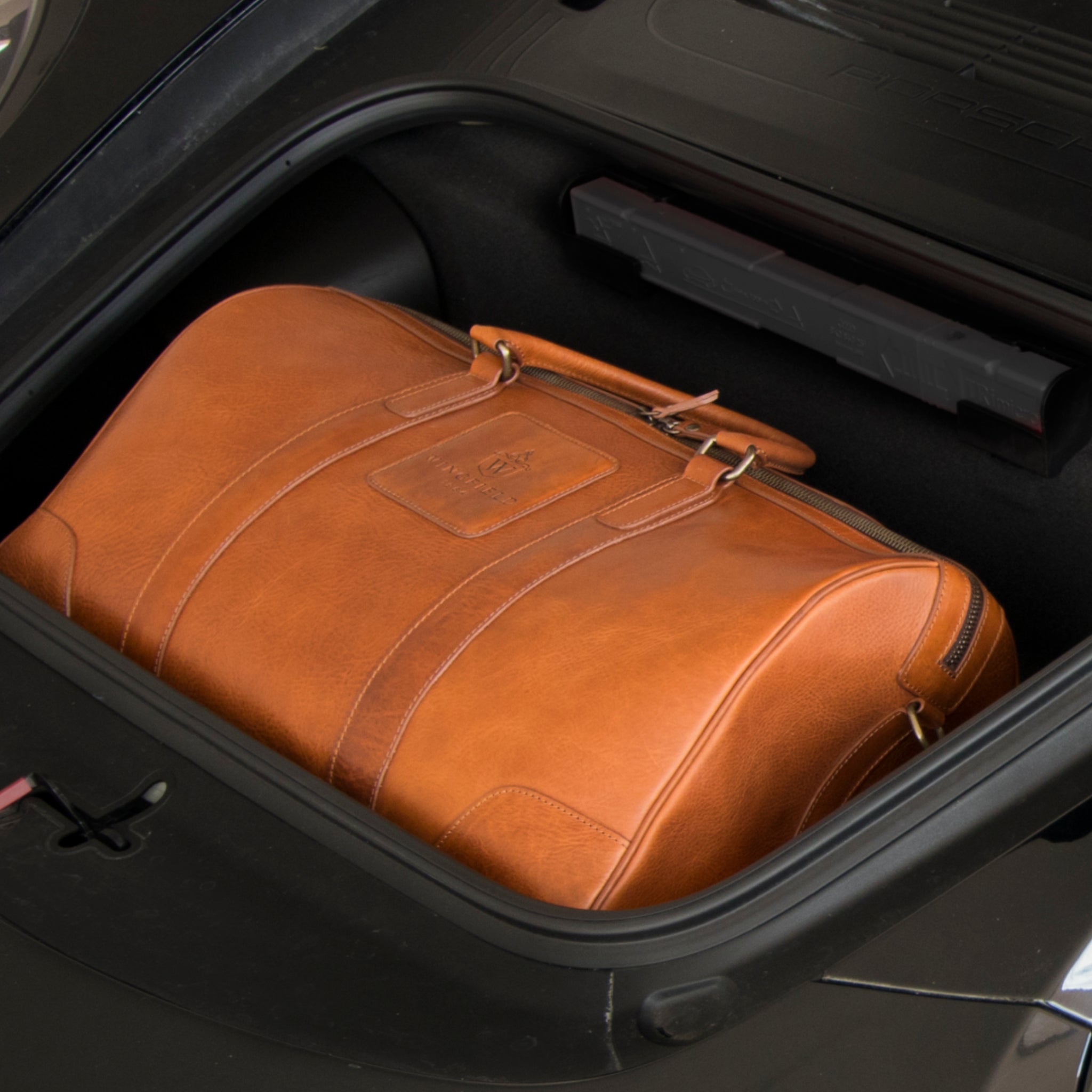 Large full-leather duffel bag with zip closure, structured body, carry handles, adjustable shoulder strap, ideal for travel.