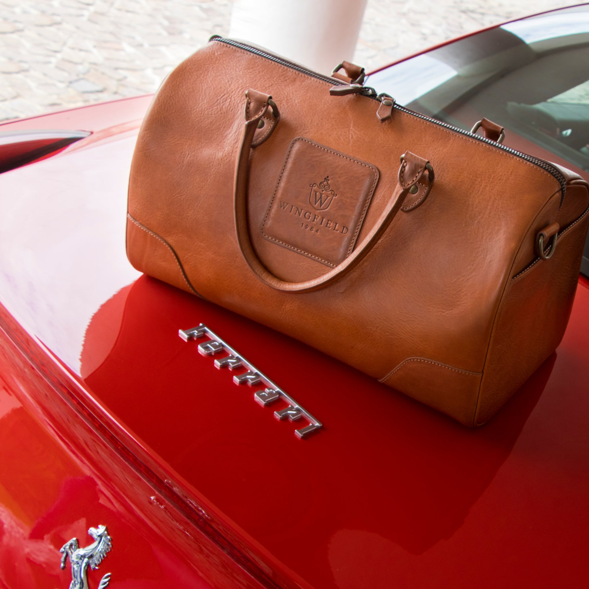 Full-grain leather duffel bag with zip closure, structured shape, carry handles, and adjustable shoulder strap, compact sleek