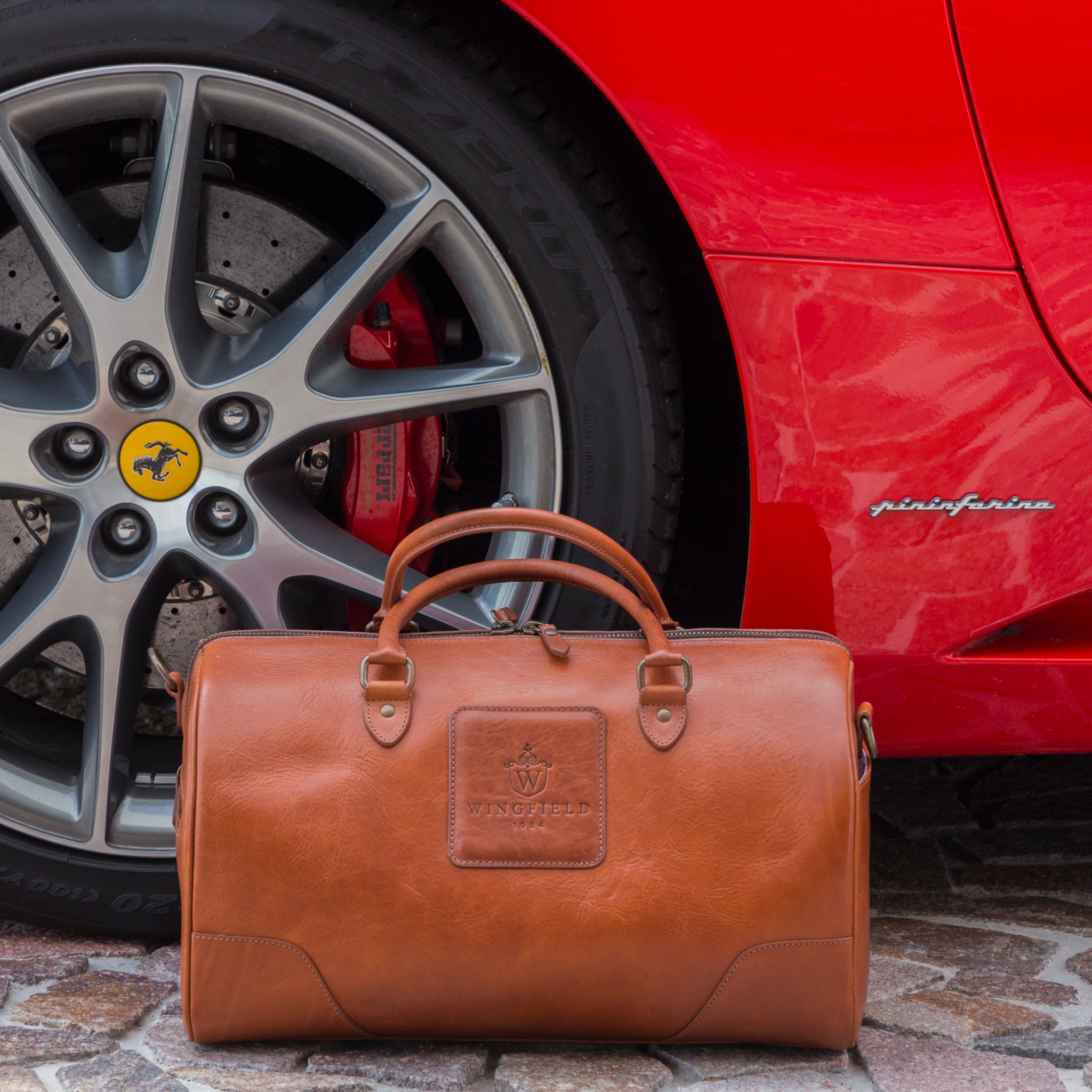 Full-grain leather duffel bag with zip closure, structured shape, carry handles, and adjustable shoulder strap, compact sleek