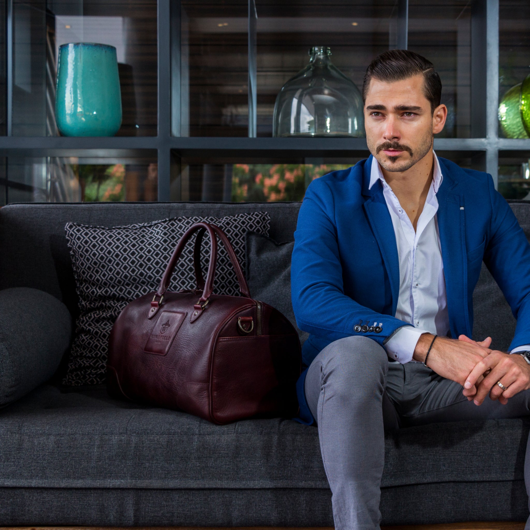 Full-grain leather duffel bag with zip closure, structured shape, carry handles, and adjustable shoulder strap, compact sleek