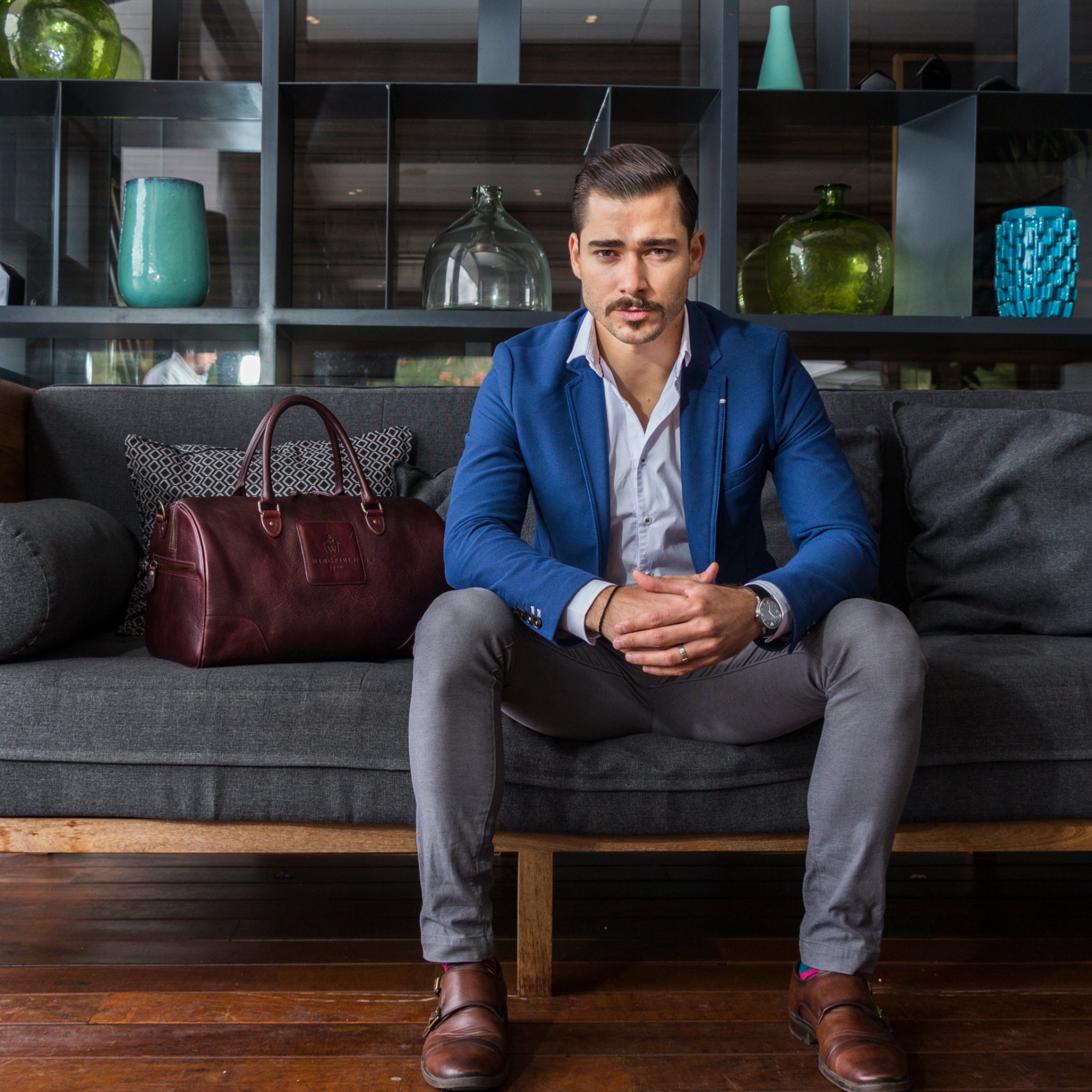 Full-grain leather duffel bag with zip closure, structured shape, carry handles, and adjustable shoulder strap, compact sleek