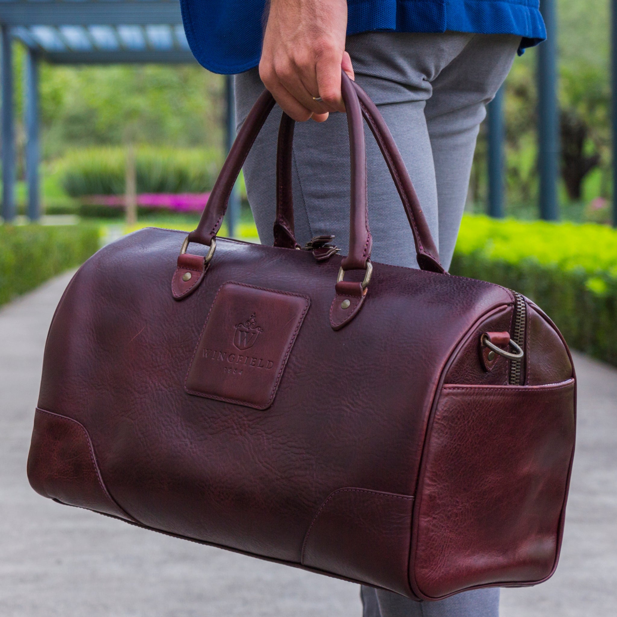 Full-grain leather duffel bag with zip closure, structured shape, carry handles, and adjustable shoulder strap, compact sleek