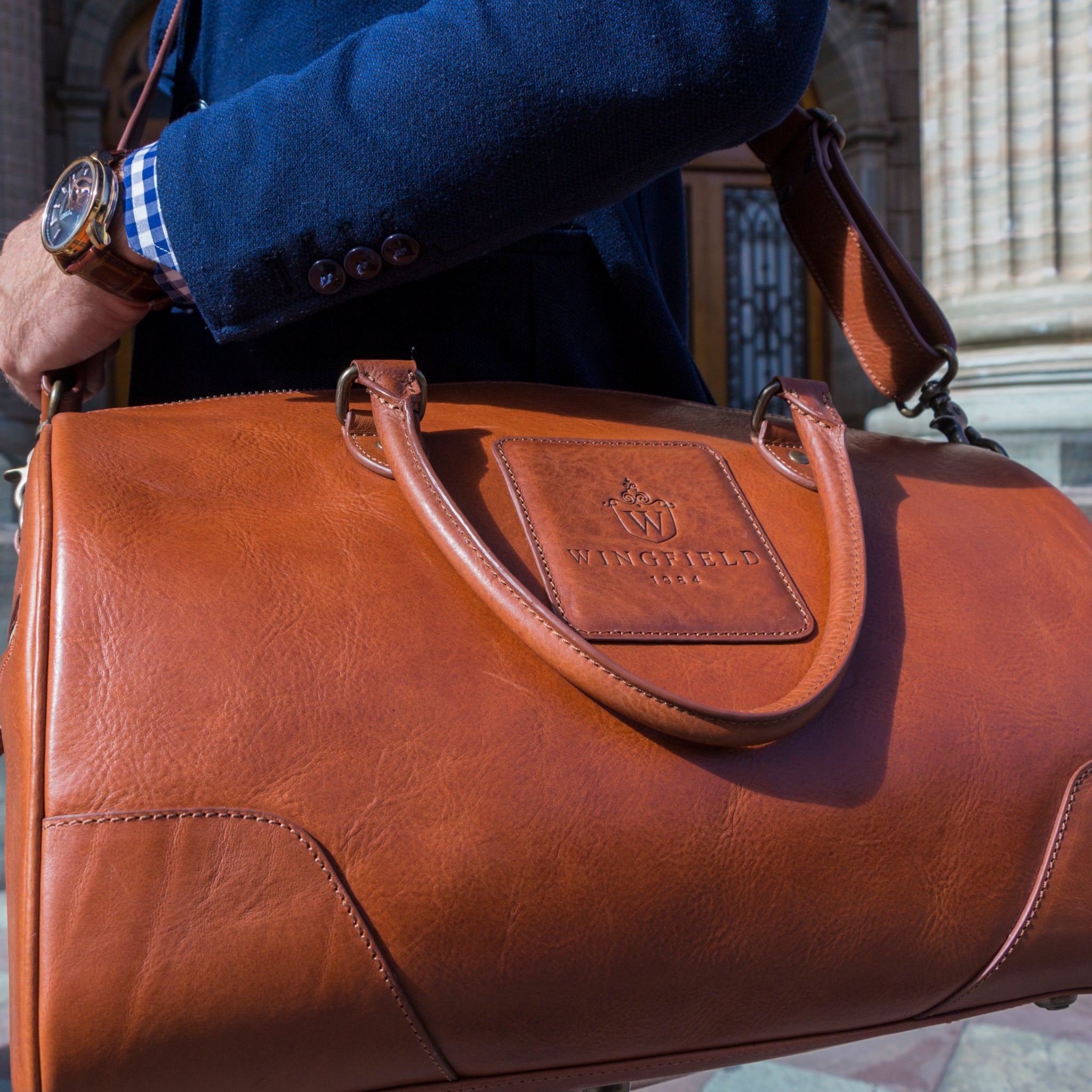 Full-grain leather duffel bag with zip closure, structured shape, carry handles, and adjustable shoulder strap, compact sleek