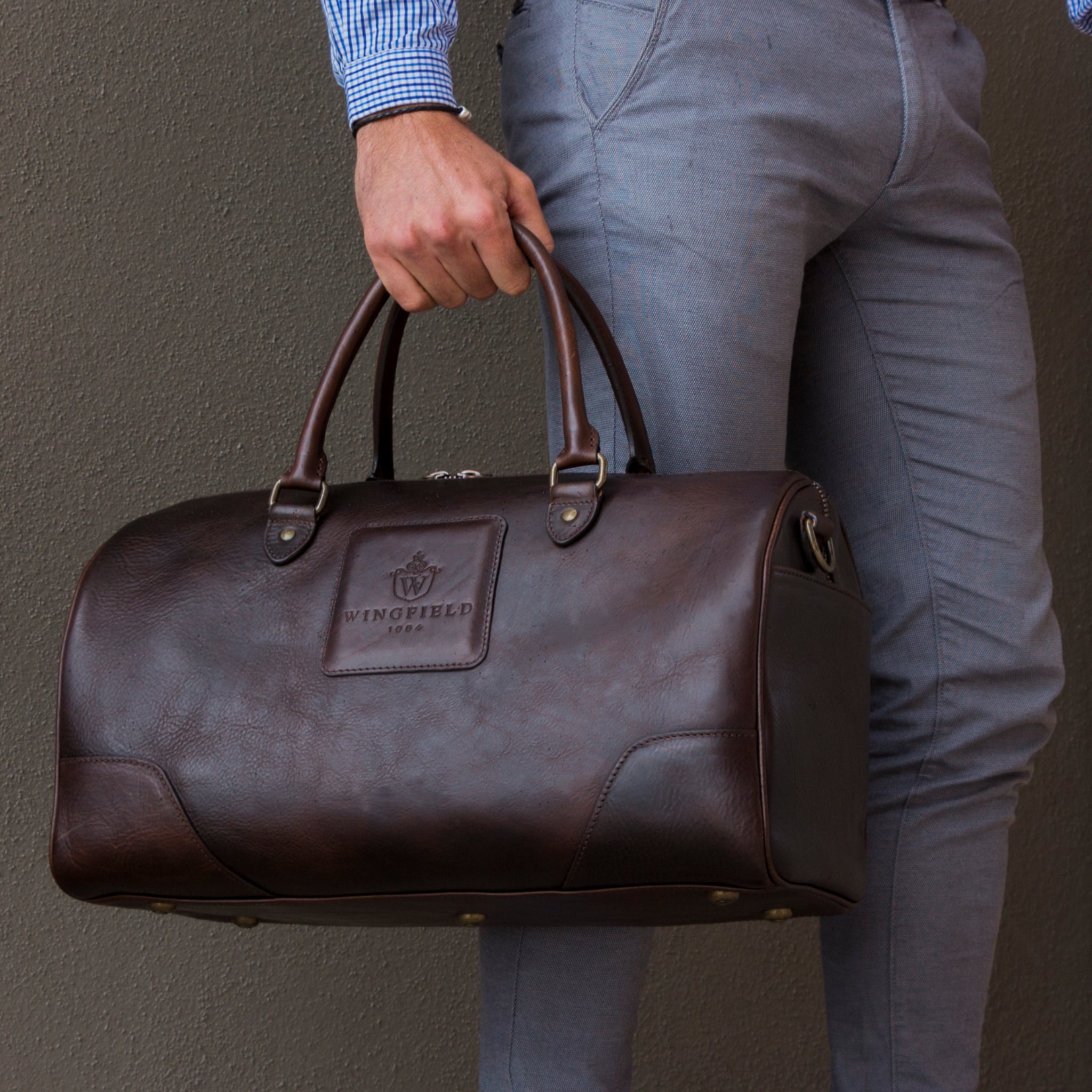 Full-grain leather duffel bag with zip closure, structured shape, carry handles, and adjustable shoulder strap, compact sleek