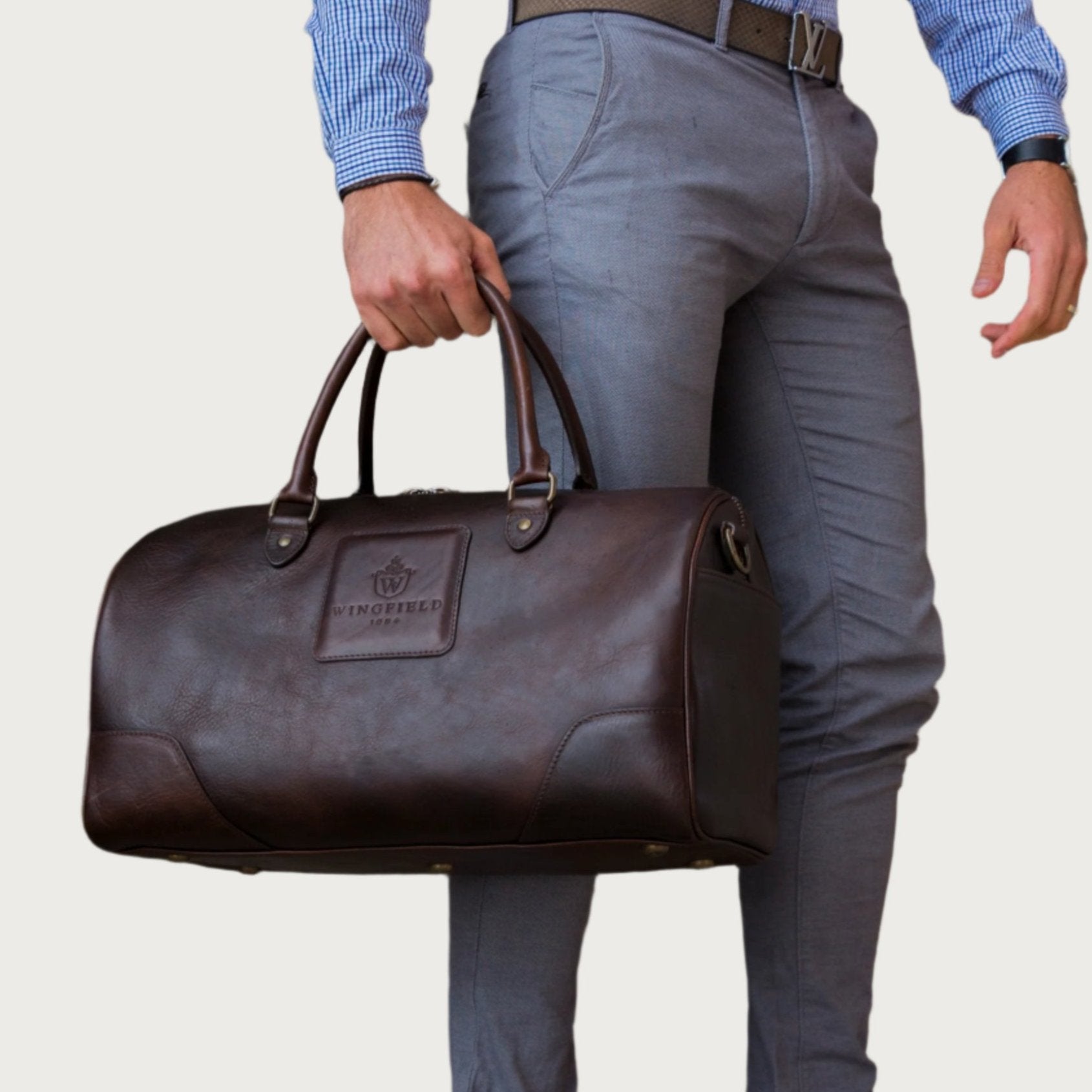 Full-grain leather duffel bag with zip closure, structured shape, carry handles, and adjustable shoulder strap, compact sleek