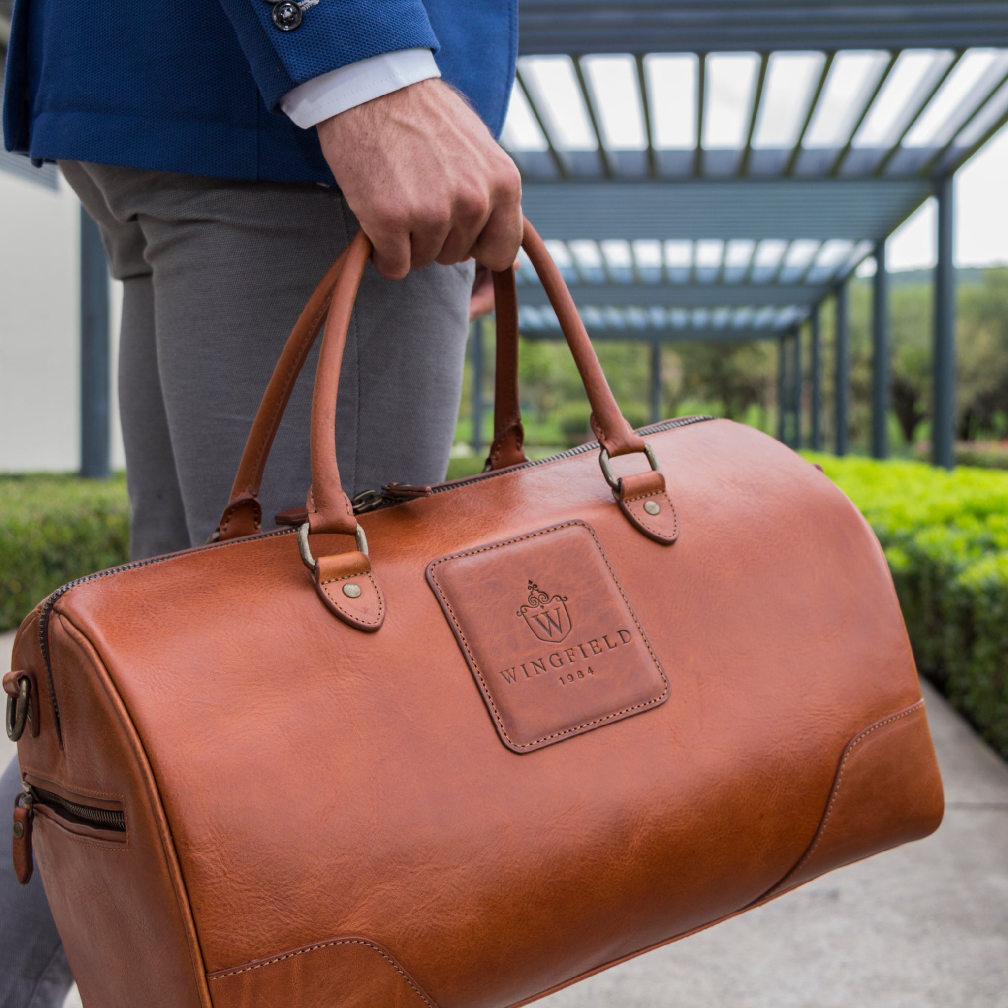 Full-grain leather duffel bag with zip closure, structured shape, carry handles, and adjustable shoulder strap, compact sleek