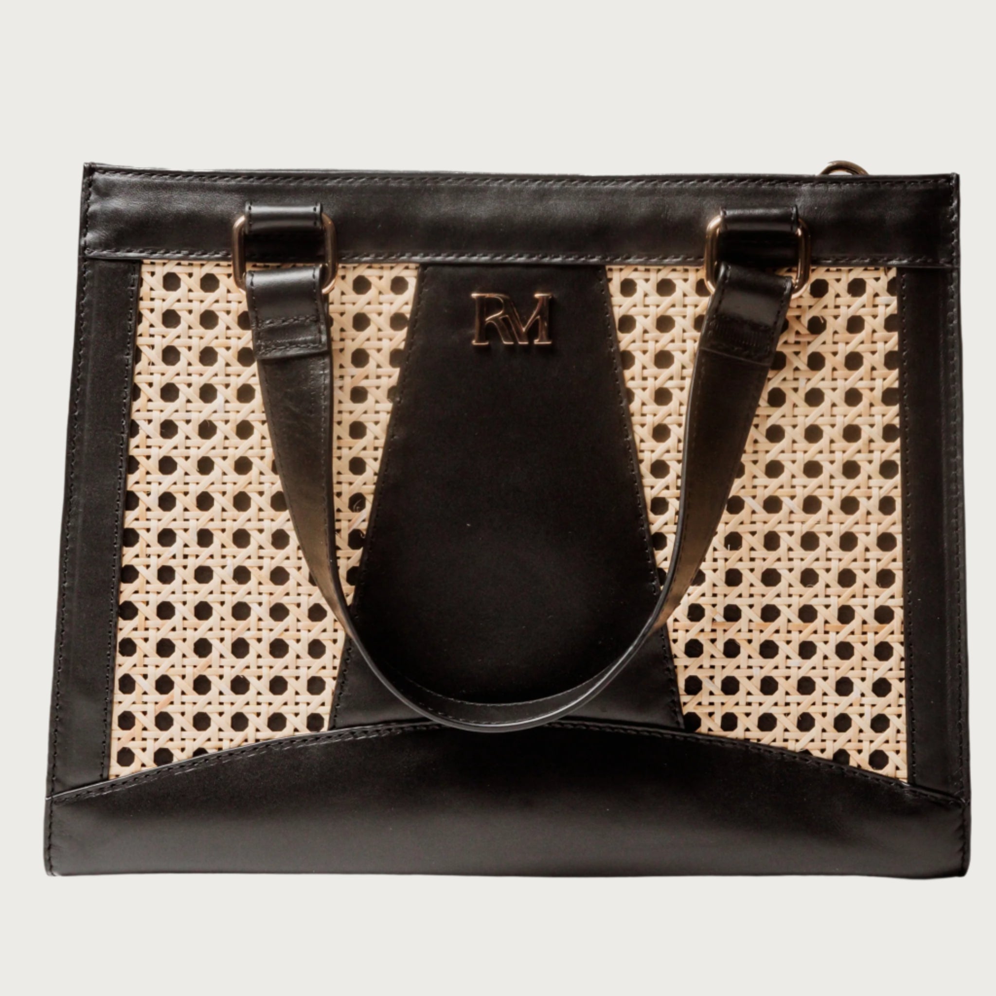 Wicker and black leather tote bag with structured silhouette, cutout handles, inner lining, and artisanal woven texture.