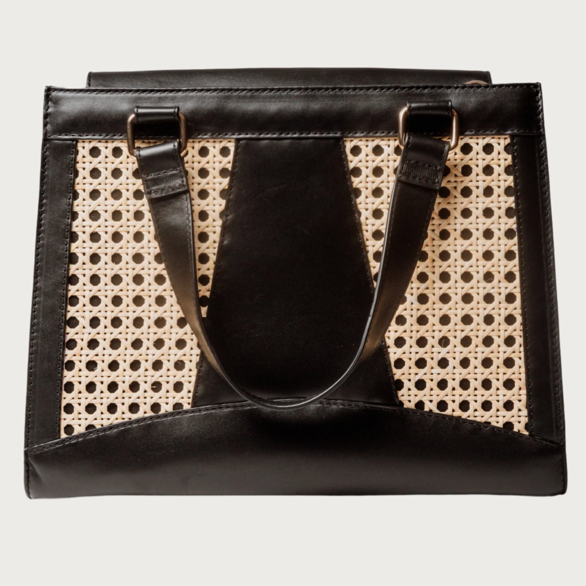 Wicker and black leather tote bag with structured silhouette, cutout handles, inner lining, and artisanal woven texture.