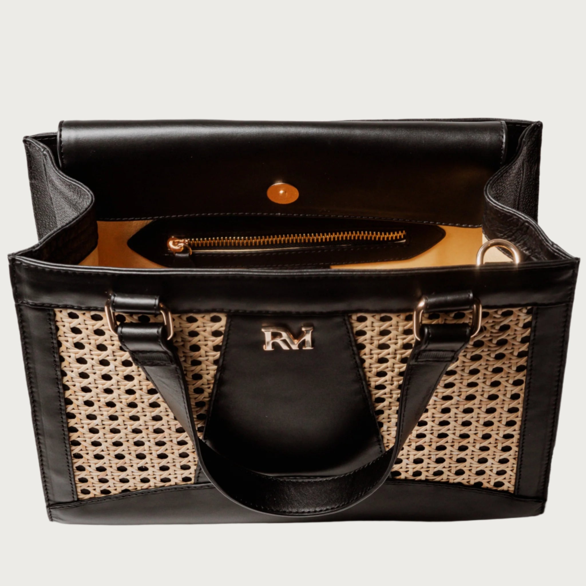 Wicker and black leather tote bag with structured silhouette, cutout handles, inner lining, and artisanal woven texture.