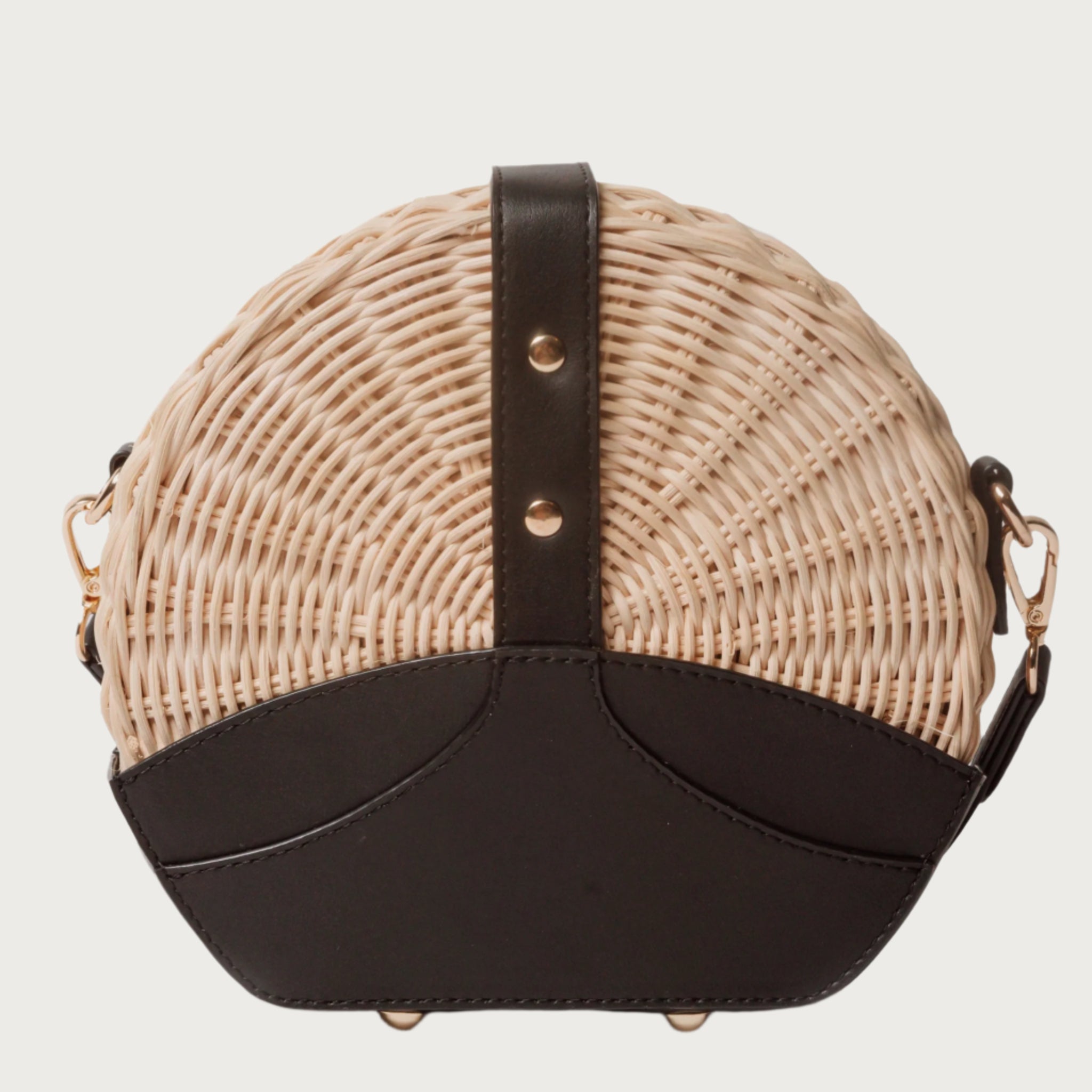 Round wicker and black leather crossbody bag with flap closure, gold chain strap, and structured shape unique eye-catching.