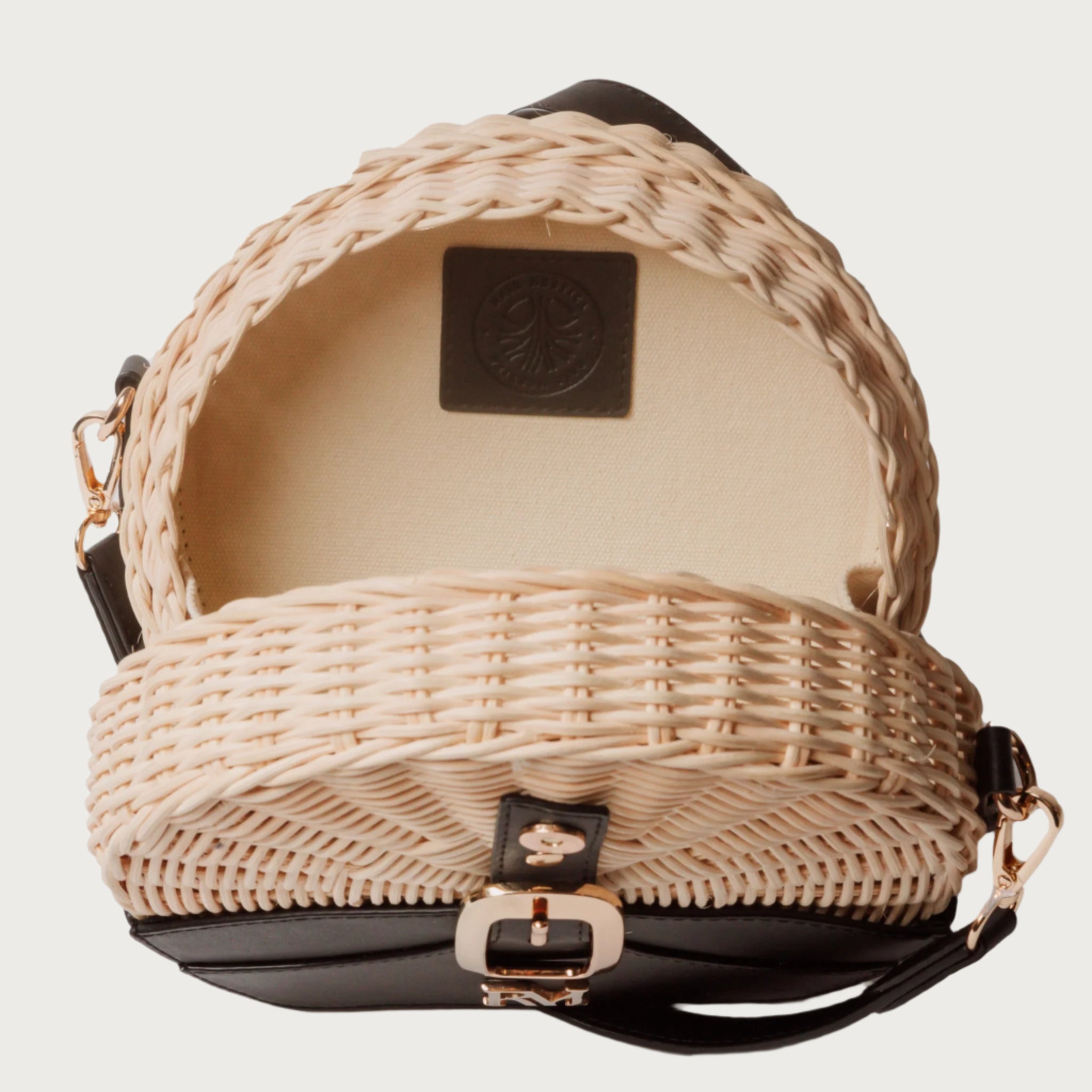 Round wicker and black leather crossbody bag with flap closure, gold chain strap, and structured shape unique eye-catching.