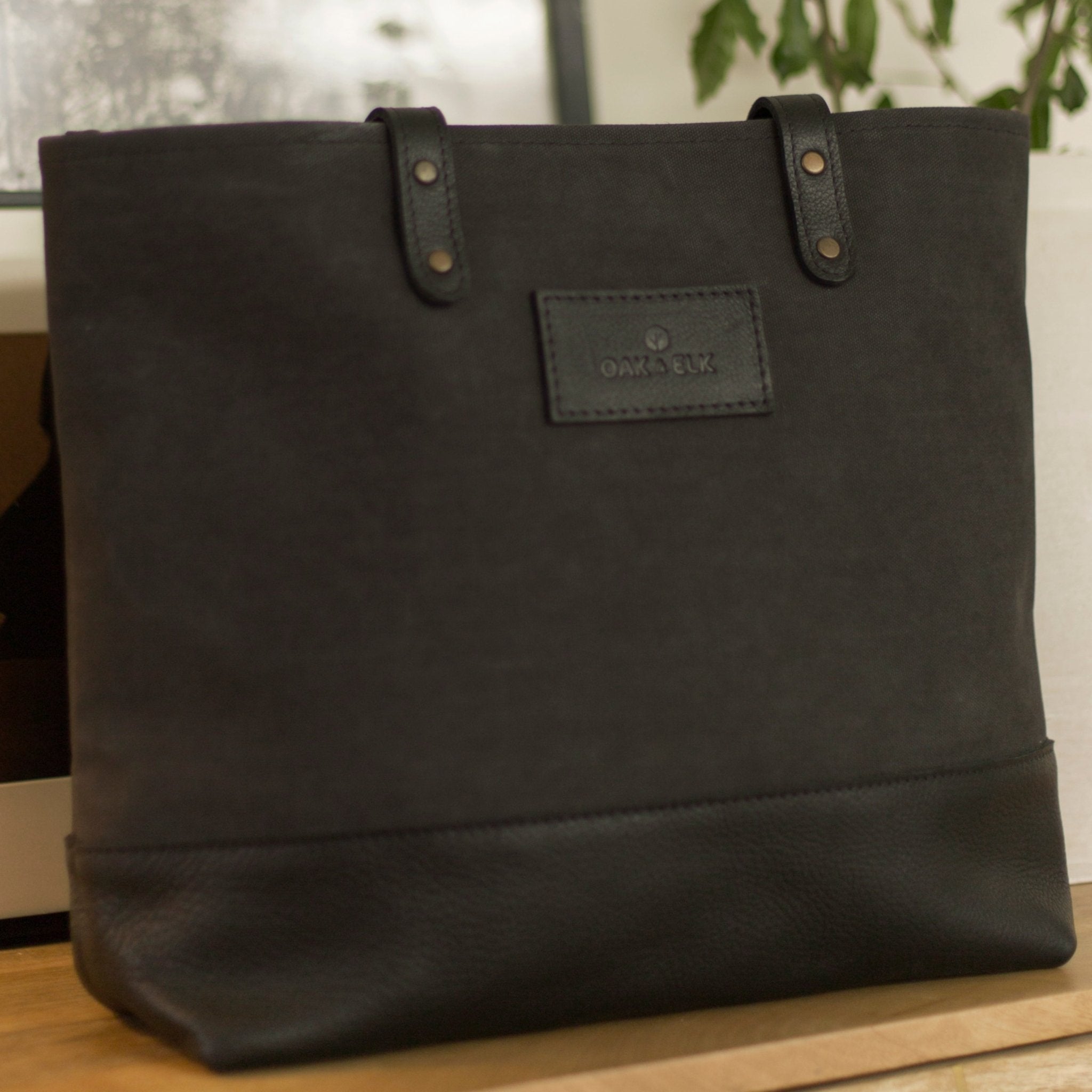 Canvas tote bag with leather trim, double shoulder straps, minimalist design, and roomy interior — ideal for daily use.