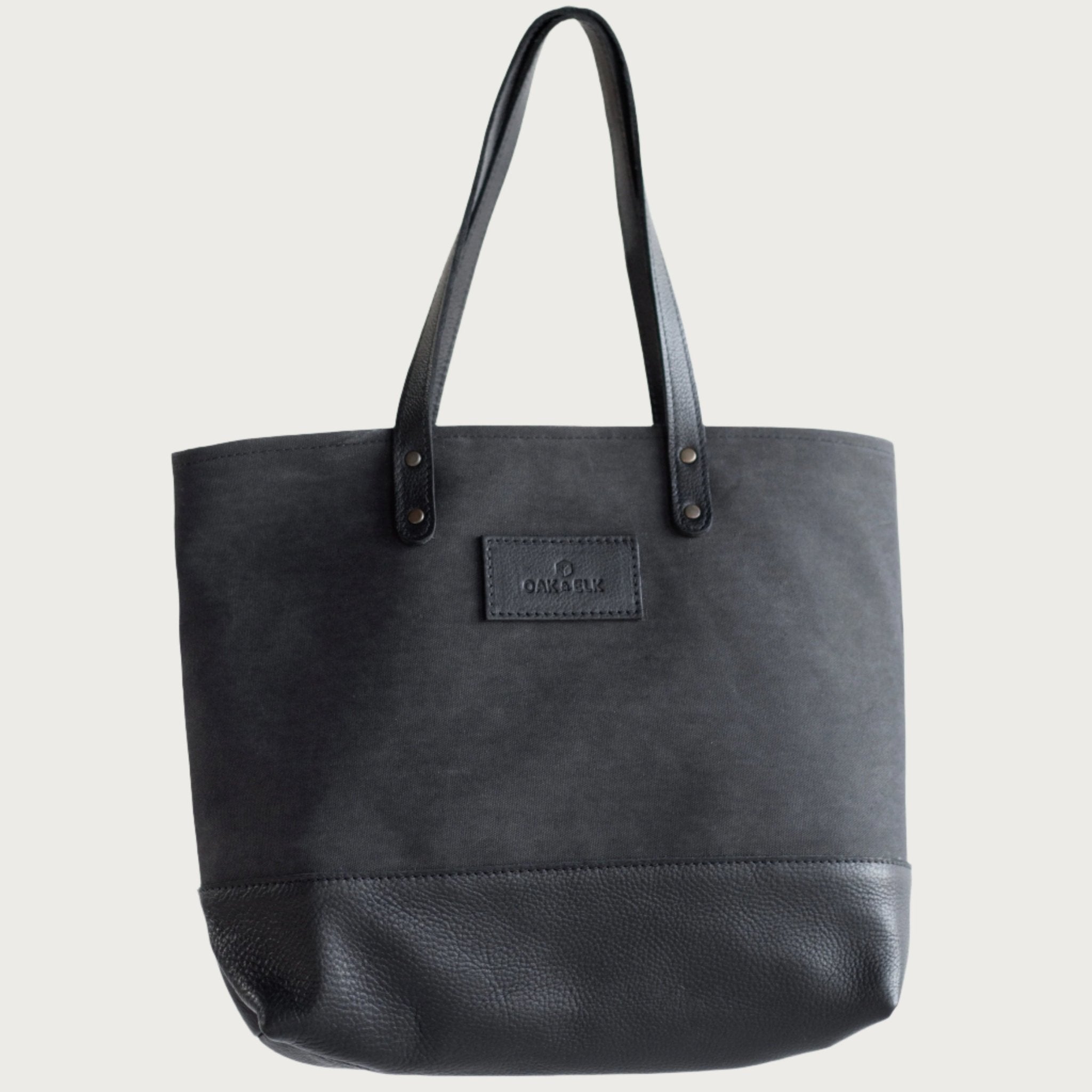 Canvas tote bag with leather trim, double shoulder straps, minimalist design, and roomy interior — ideal for daily use.