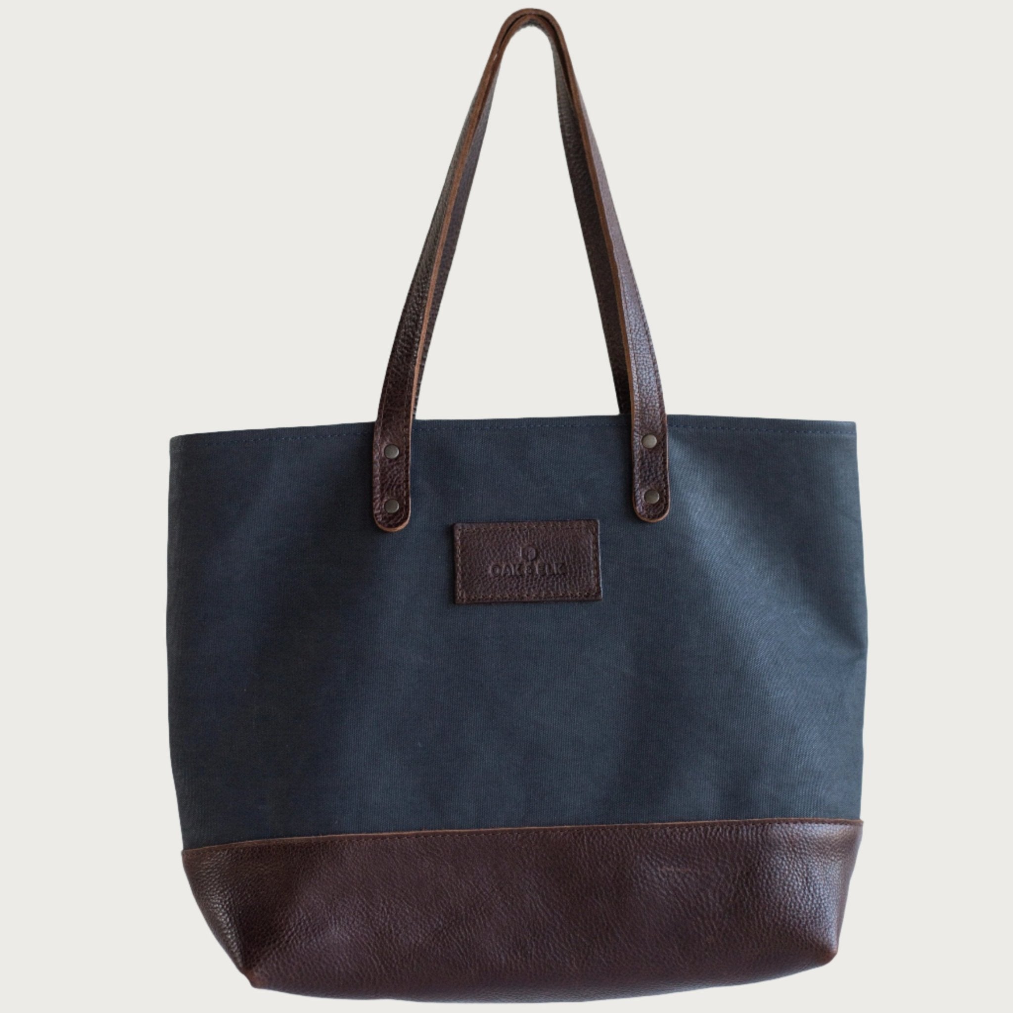 Canvas tote bag with leather trim, double shoulder straps, minimalist design, and roomy interior — ideal for daily use.