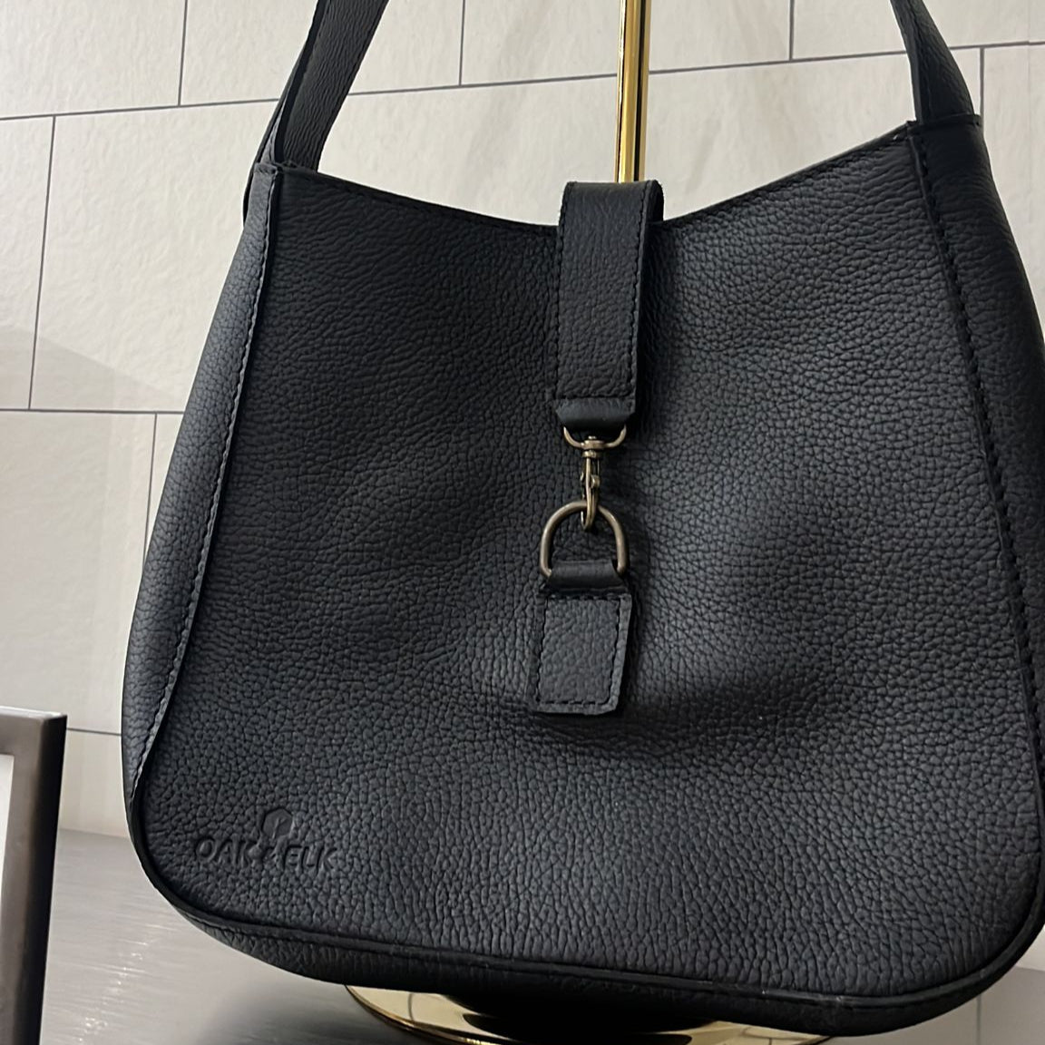 Full-grain leather shoulder bag with minimalist design, adjustable strap, interior pocket, soft structure, everyday essential