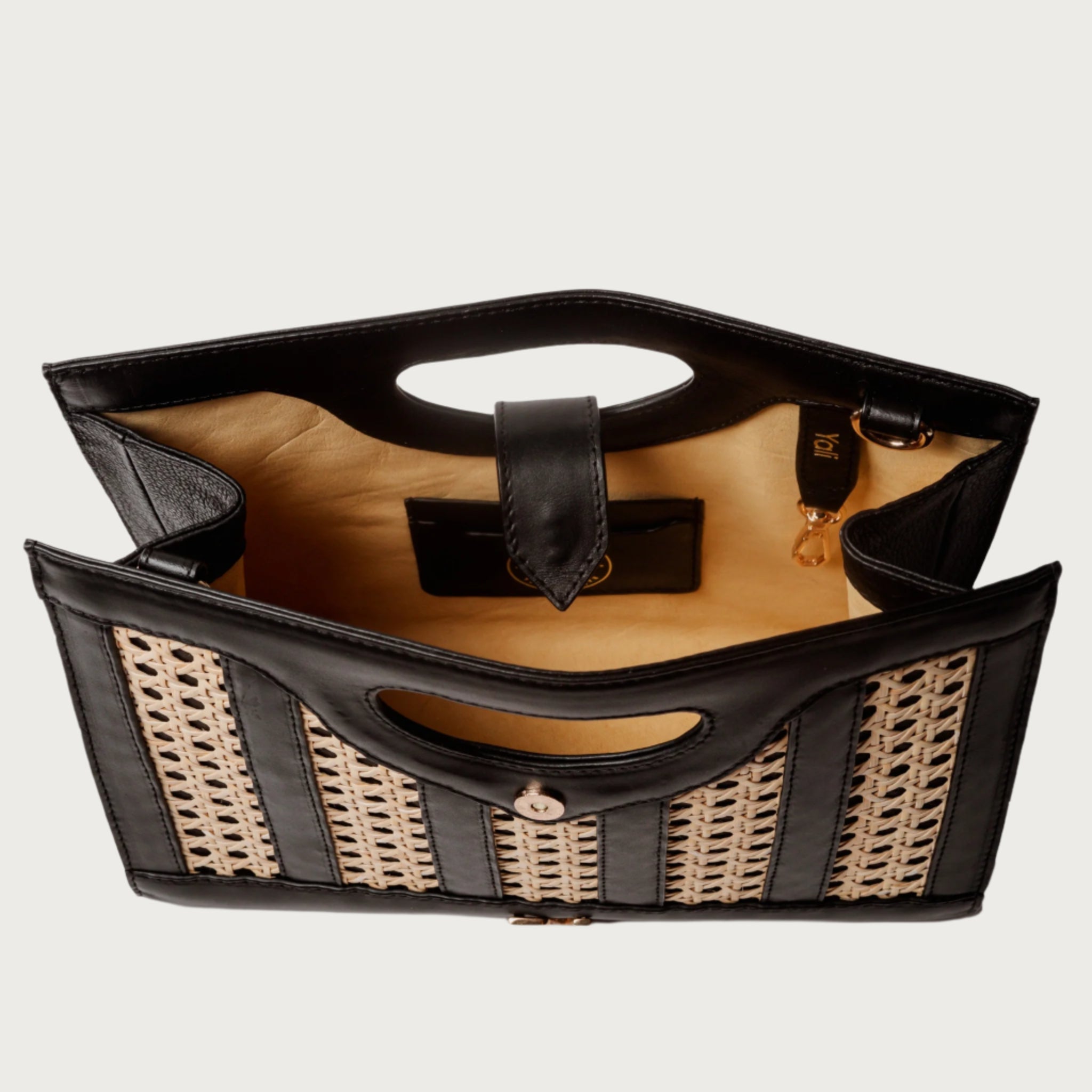 Handwoven wicker and black leather clutch with structured silhouette, cutout handle, and fabric lining bold elegant design