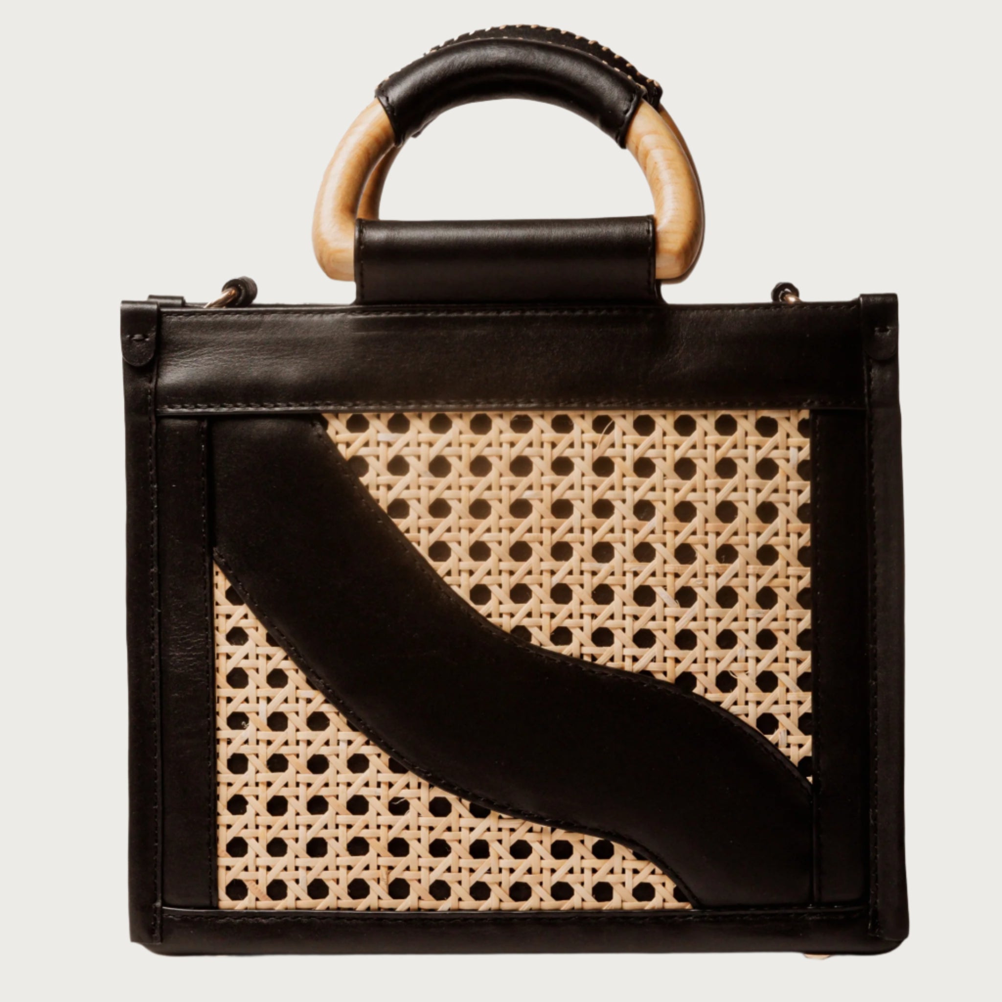 Structured square handbag with handwoven cane body, black leather trim, top handles, and crossbody strap — bold refined look