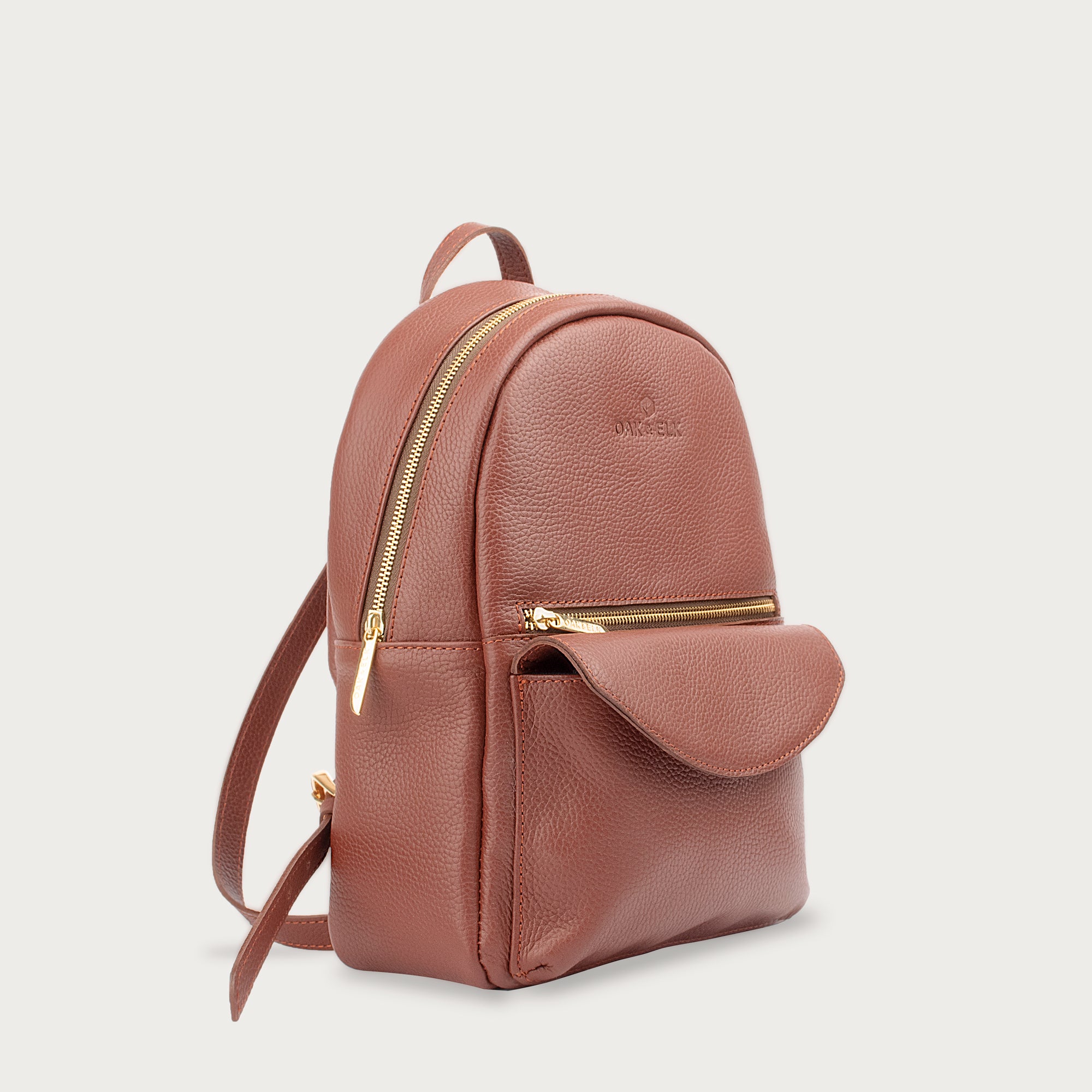 Leather backpack with smooth finish, adjustable straps, front zipper pocket, and gold hardware – Emma by OAK & ELK.