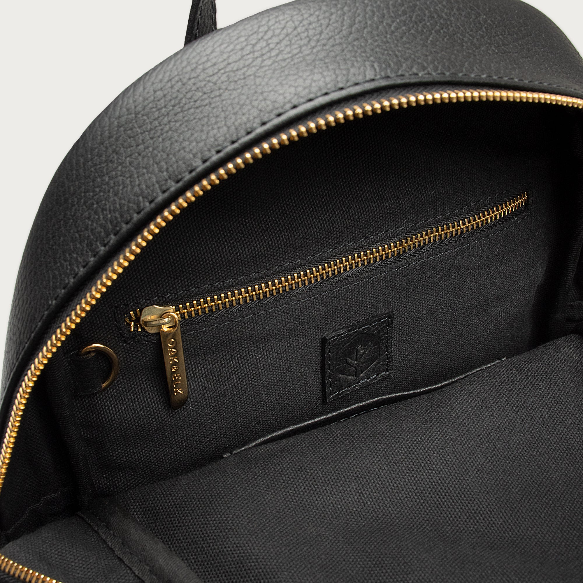Leather backpack with smooth finish, adjustable straps, front zipper pocket, and gold hardware – Emma by OAK & ELK.
