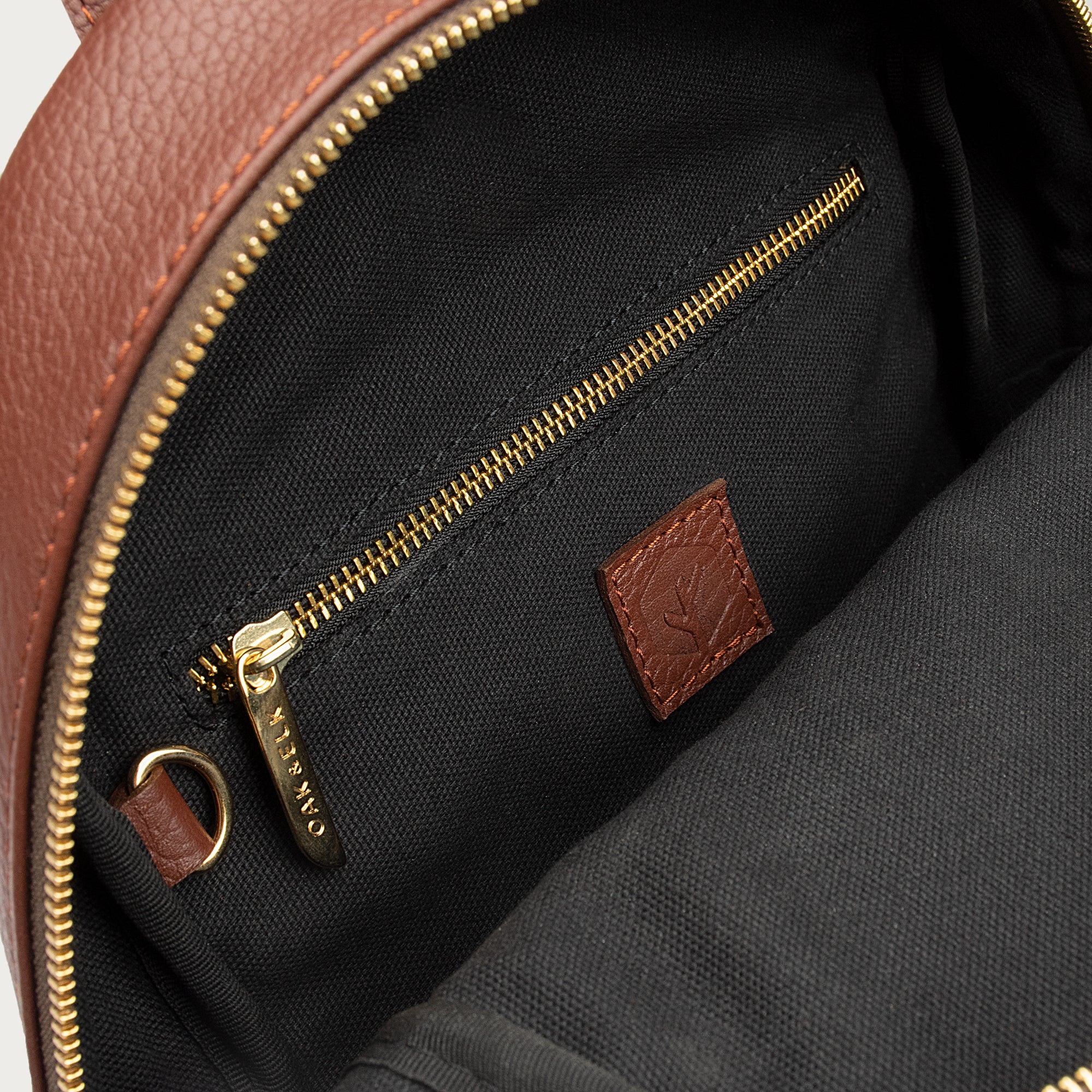 Leather backpack with smooth finish, adjustable straps, front zipper pocket, and gold hardware – Emma by OAK & ELK.