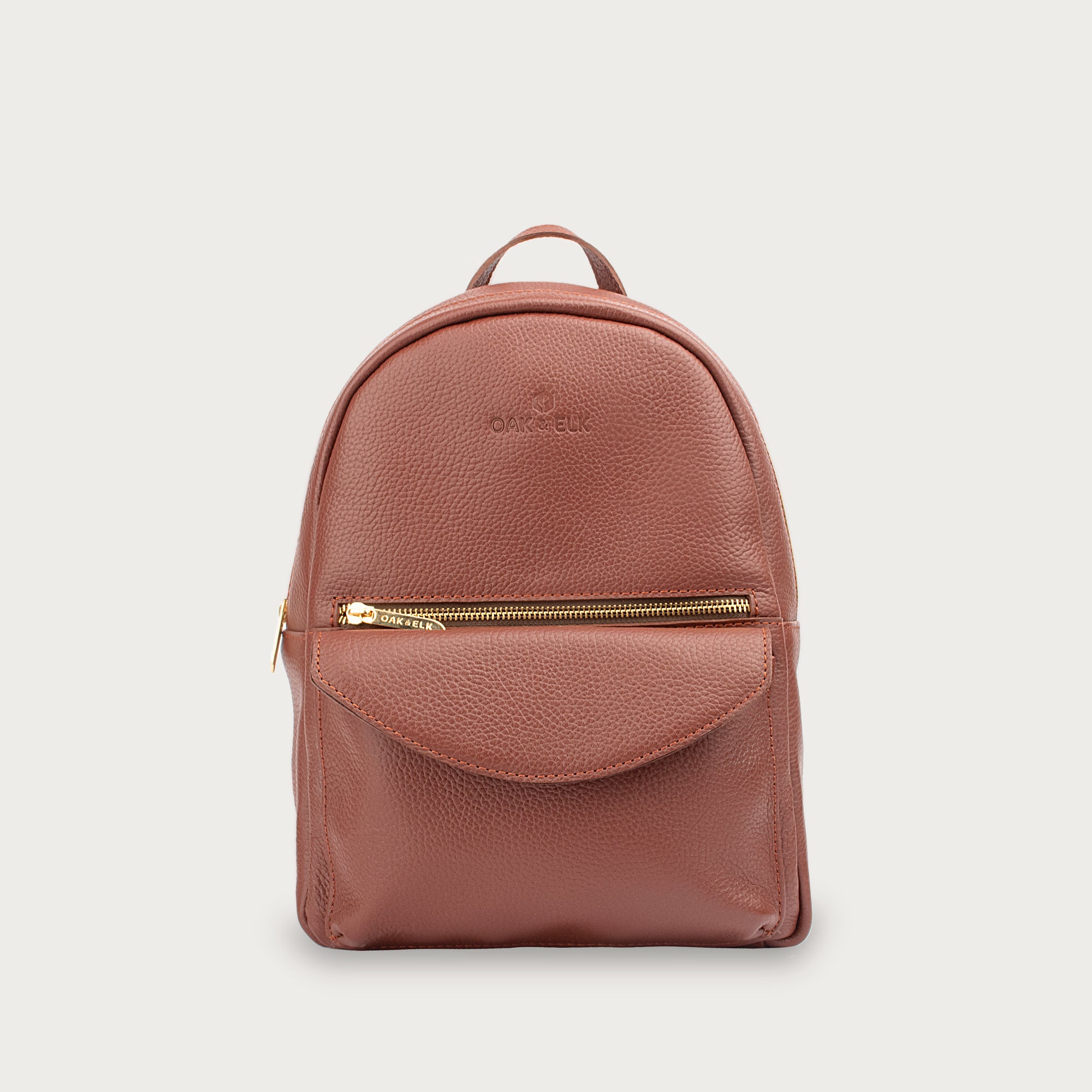 Leather backpack with smooth finish, adjustable straps, front zipper pocket, and gold hardware – Emma by OAK & ELK.