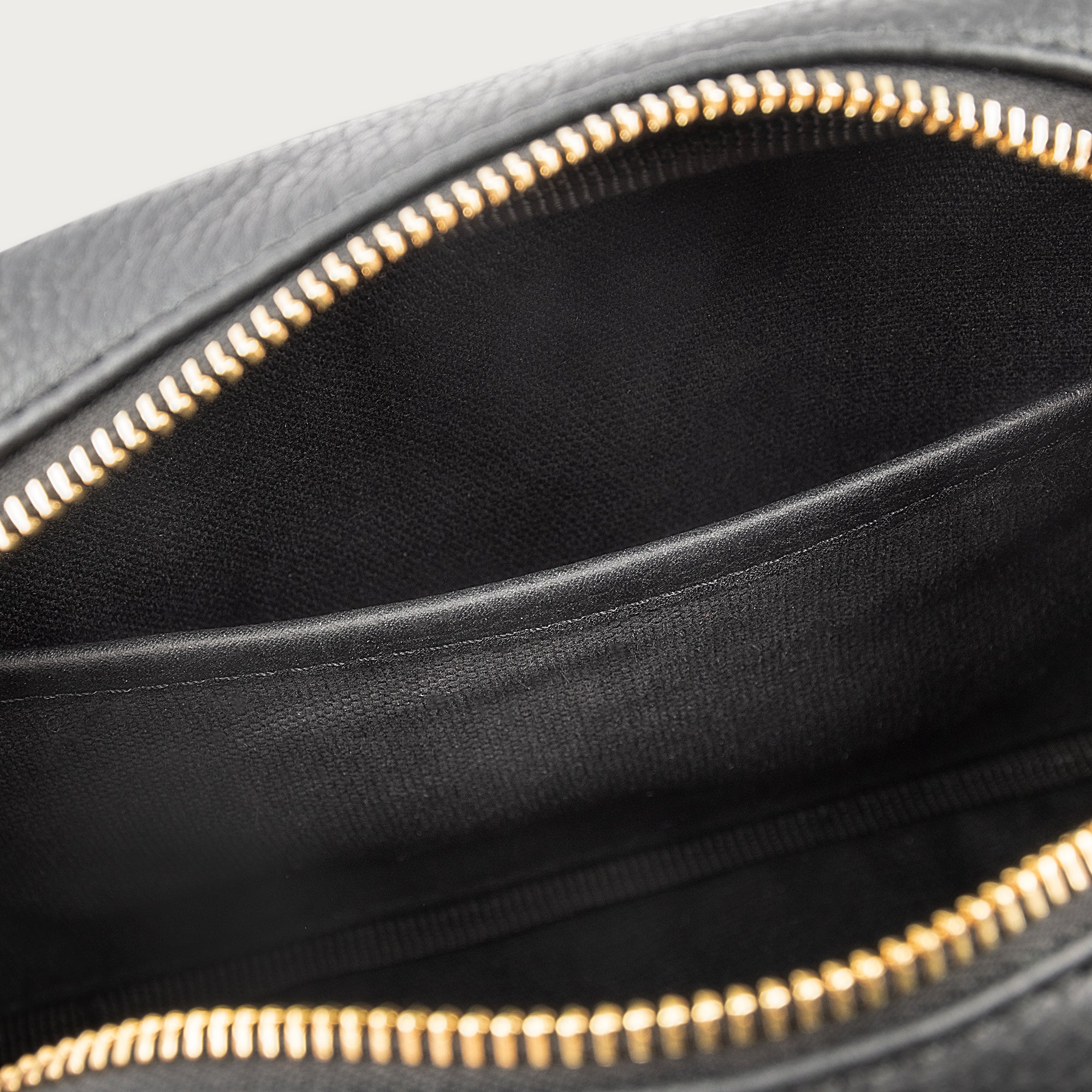 Black leather camera bag with gold zipper, adjustable crossbody strap, and compact design — ideal for essentials on the go.