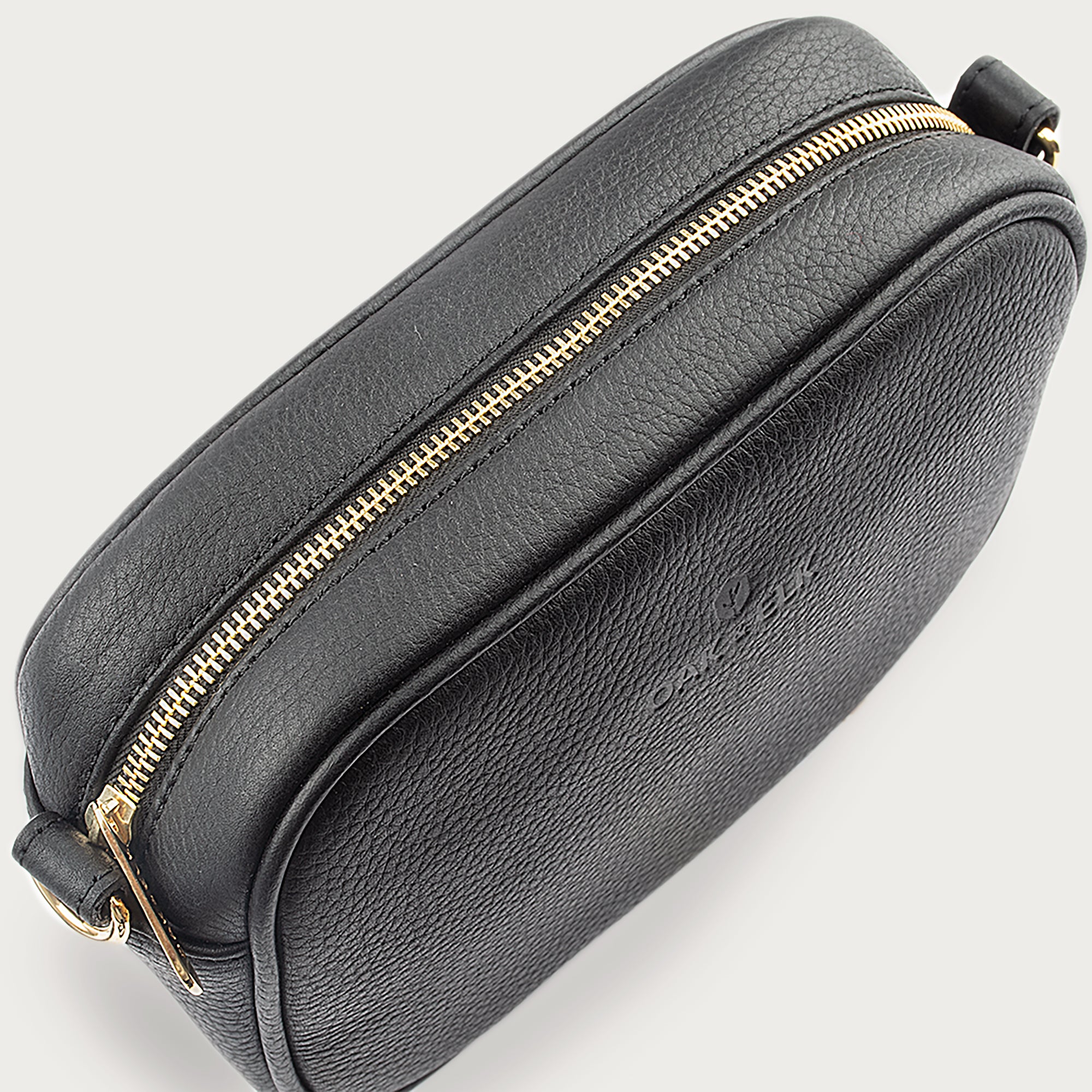 Black leather camera bag with gold zipper, adjustable crossbody strap, and compact design — ideal for essentials on the go.