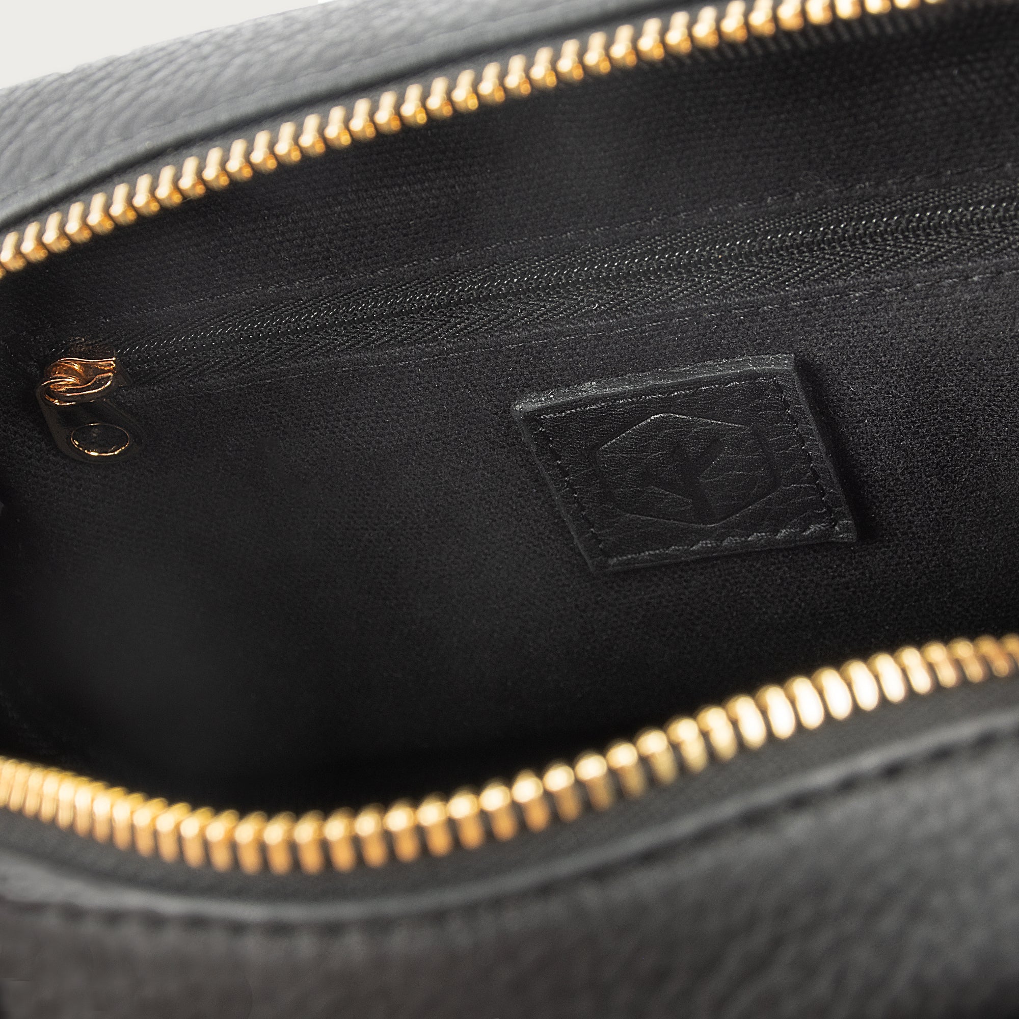 Black leather camera bag with gold zipper, adjustable crossbody strap, and compact design — ideal for essentials on the go.