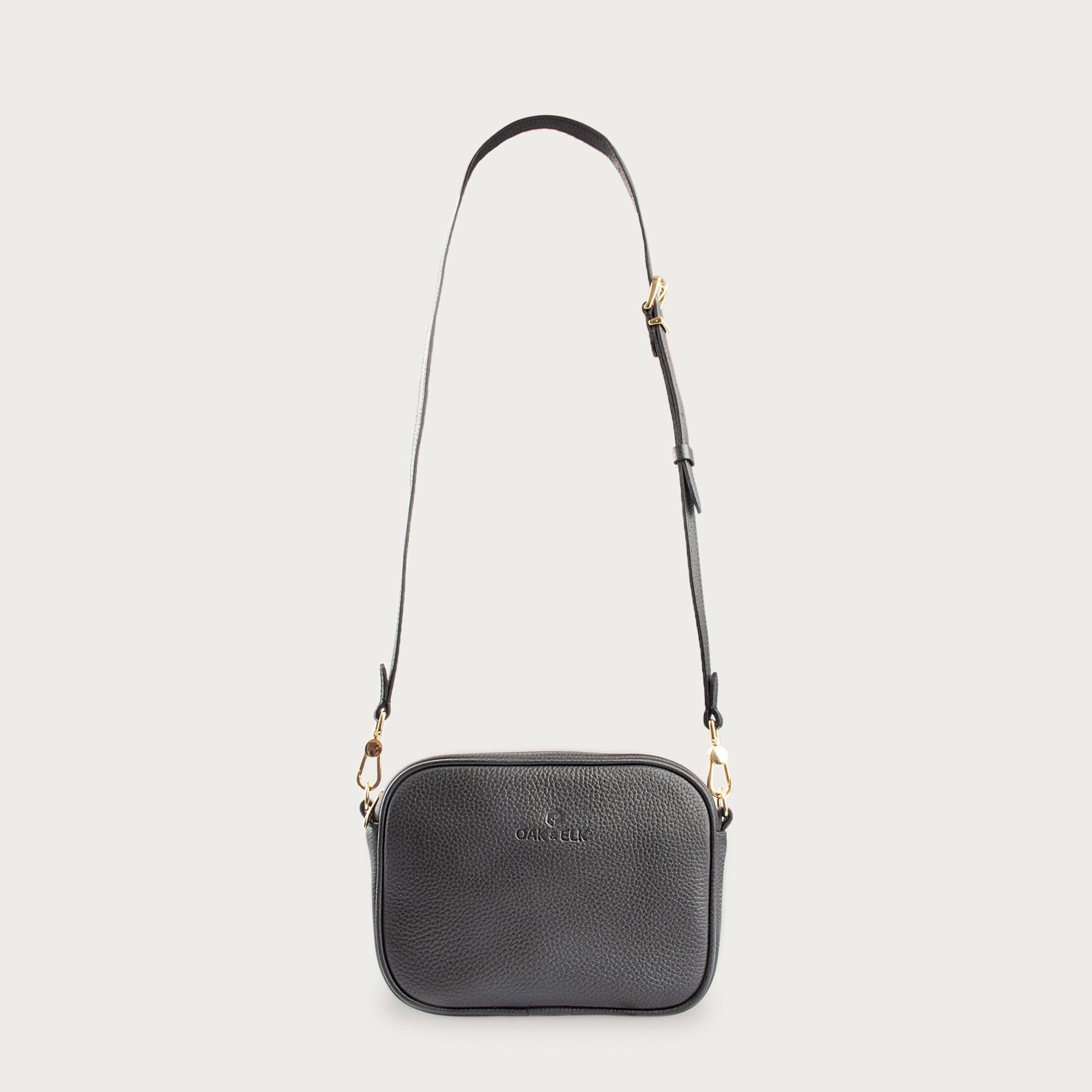 Black leather camera bag with gold zipper, adjustable crossbody strap, and compact design — ideal for essentials on the go.