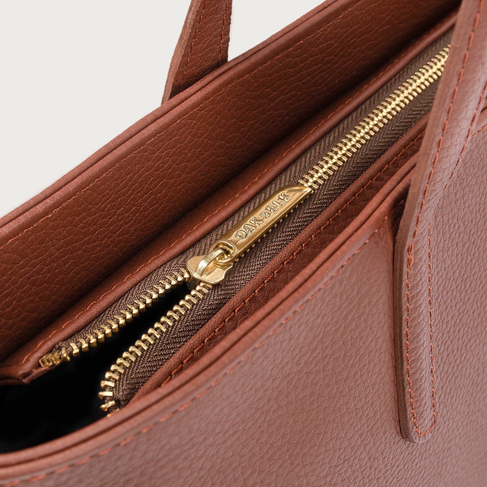 Leather tote made from top-grain leather, featuring smooth golden zipper, inner pouch, and structured design for daily use.