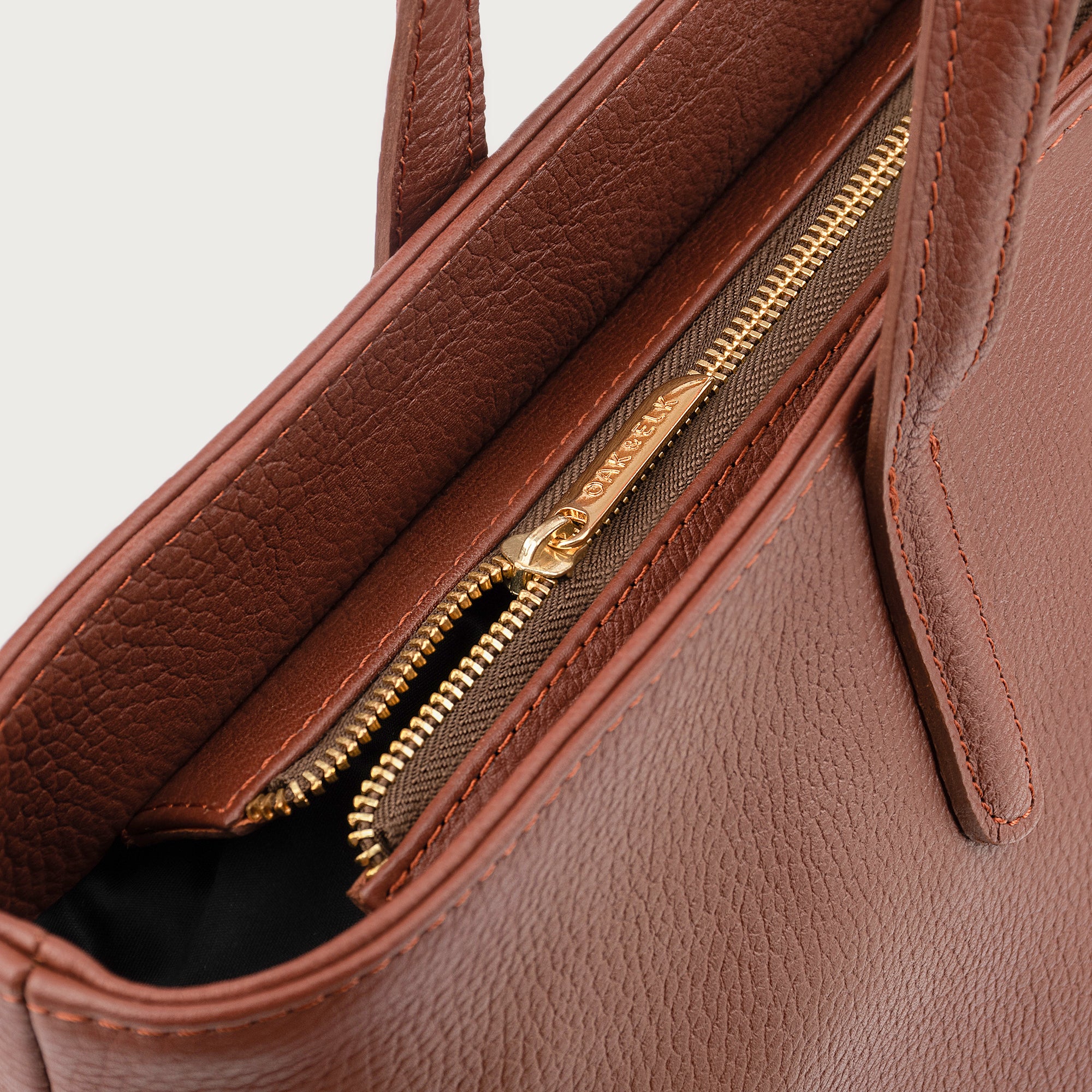 Leather tote made from top-grain leather, featuring smooth golden zipper, inner pouch, and structured design for daily use.