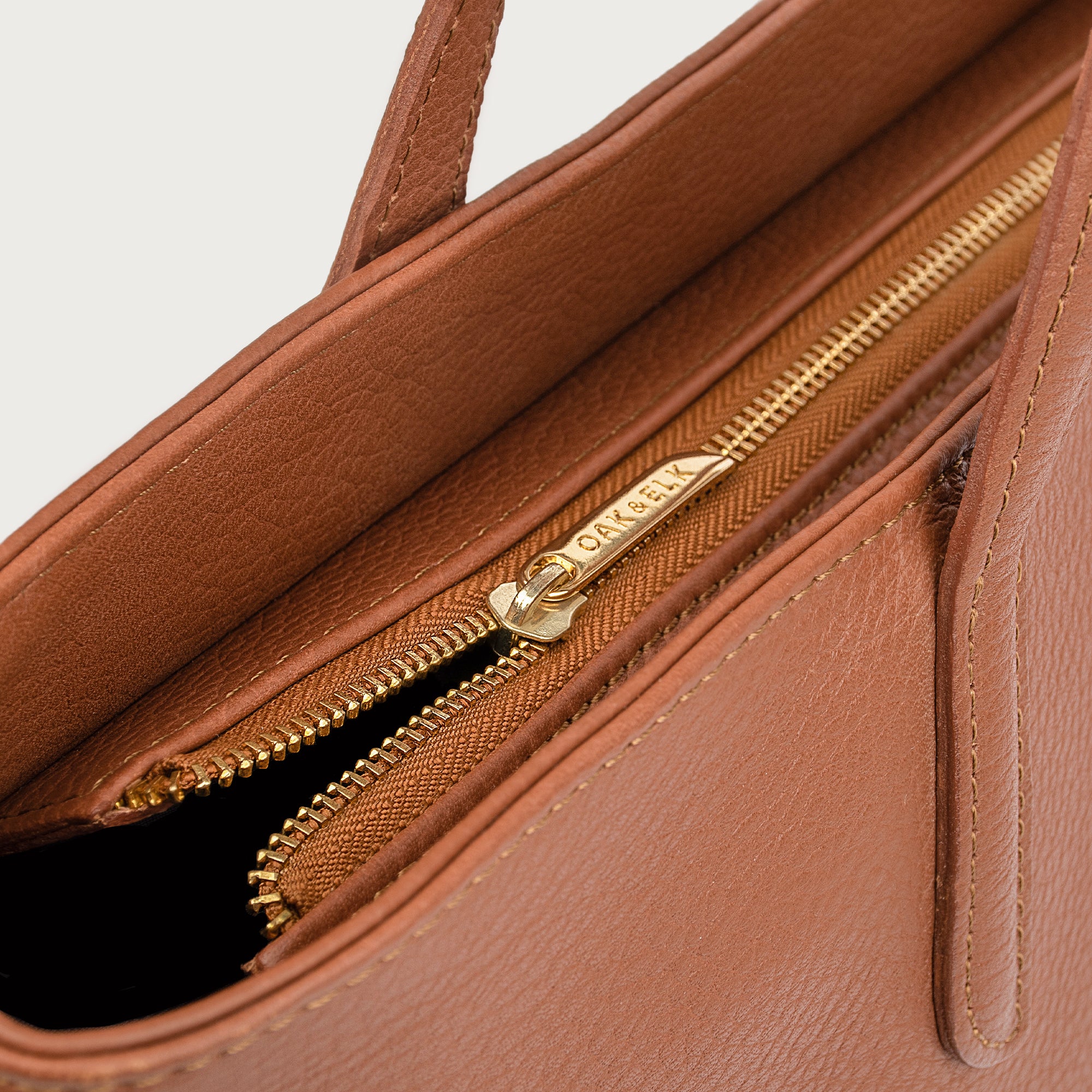 Leather tote made from top-grain leather, featuring smooth golden zipper, inner pouch, and structured design for daily use.