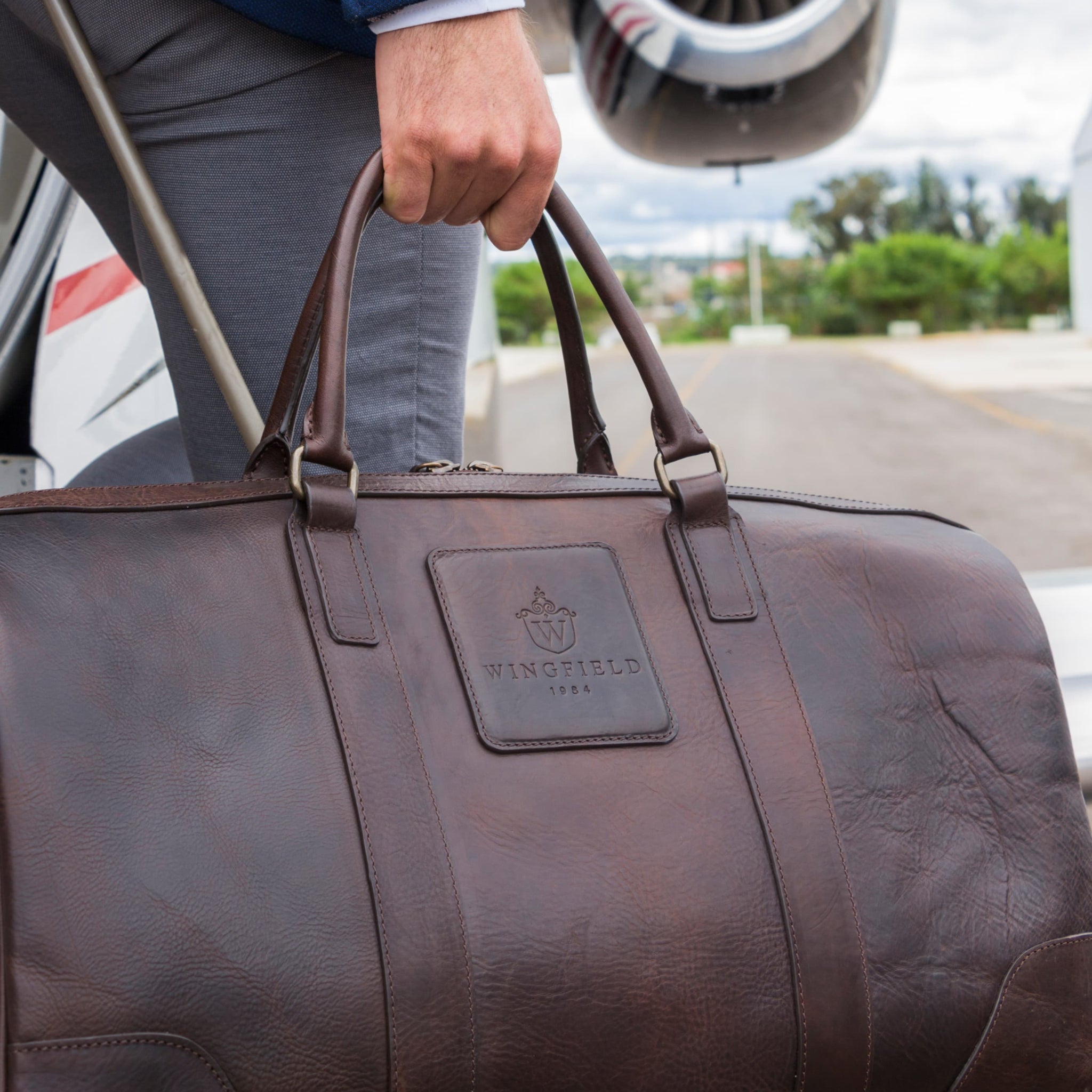 Is leather biodegradable: chocolate brown vegetable tanned leather duffel bag by OAK & ELK shown front on